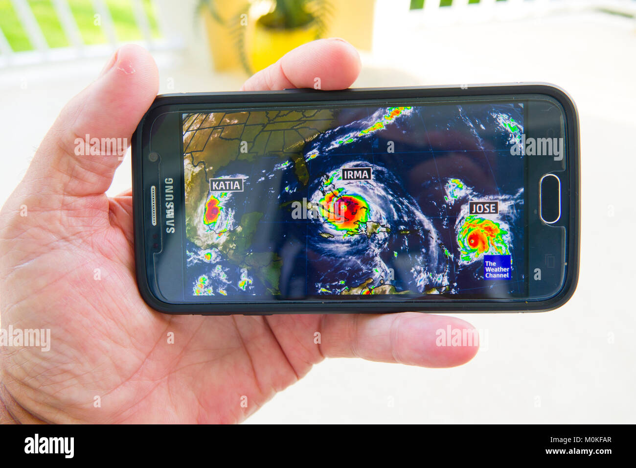 Nach einem Hurrikan Irma Warnung auf tv Fernsehen und ein Handy in der Hand gerät Smartphone Stockfoto