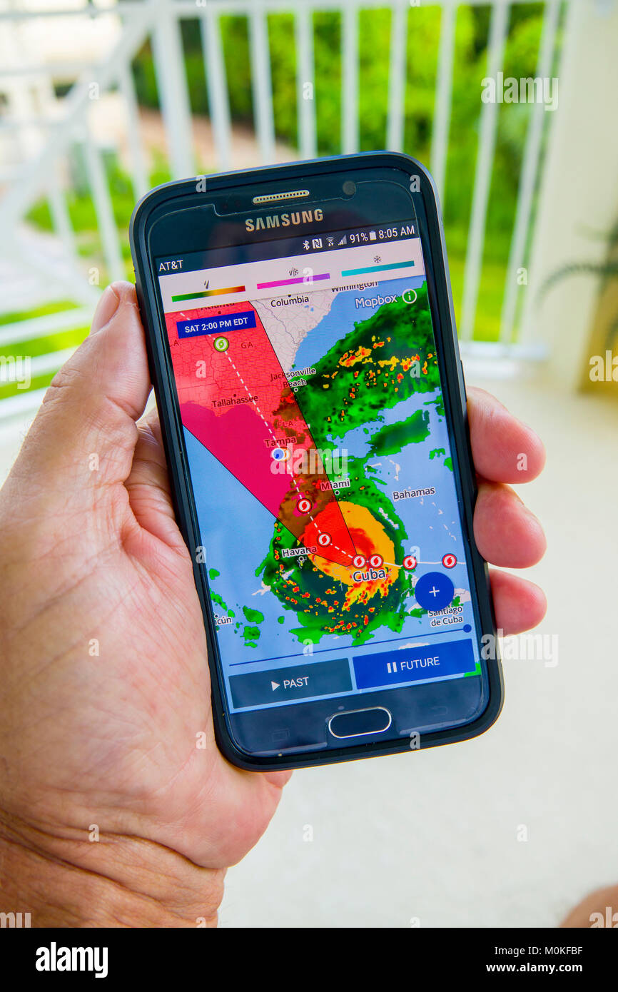 Nach einem Hurrikan Irma Warnung auf tv Fernsehen und ein Handy in der Hand gerät Smartphone Stockfoto