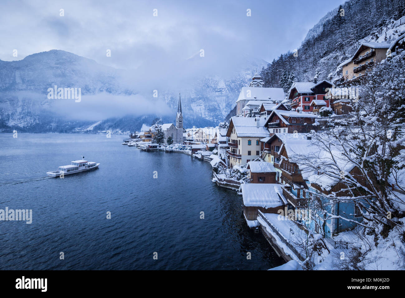 Klassische Ansicht von Hallstatt mit Schiff auf einer Moody Tag mit mystischen Nebel im Winter, Salzkammergut, Österreich Stockfoto