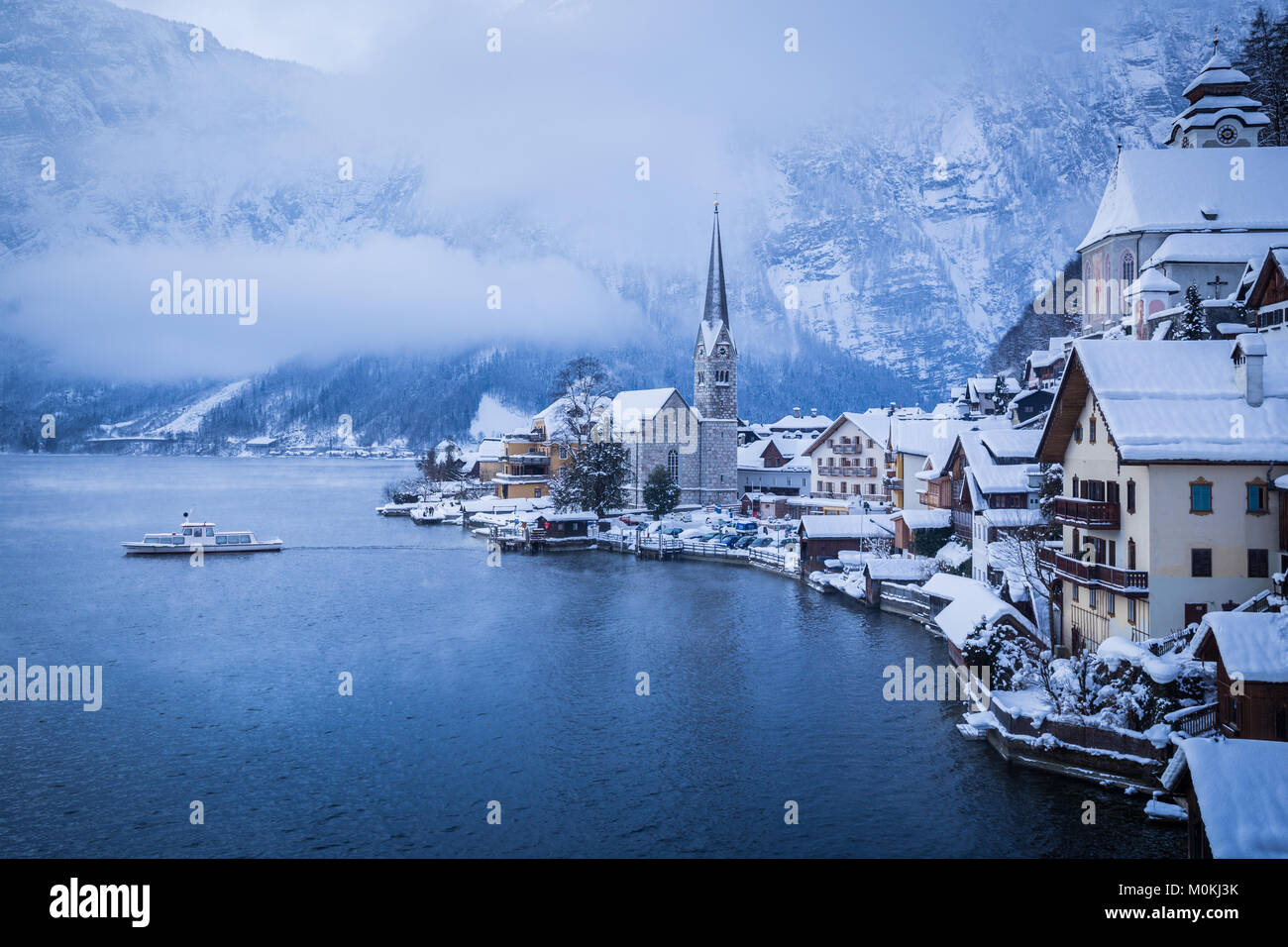 Klassische Ansicht von Hallstatt mit Schiff auf einer Moody Tag mit mystischen Nebel im Winter, Salzkammergut, Österreich Stockfoto