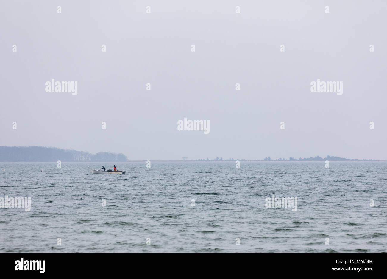 Zwei Fischer in einem kleinen Boot in der Bucht an einem nebligen Winter, Eastern Long Island, NY Stockfoto