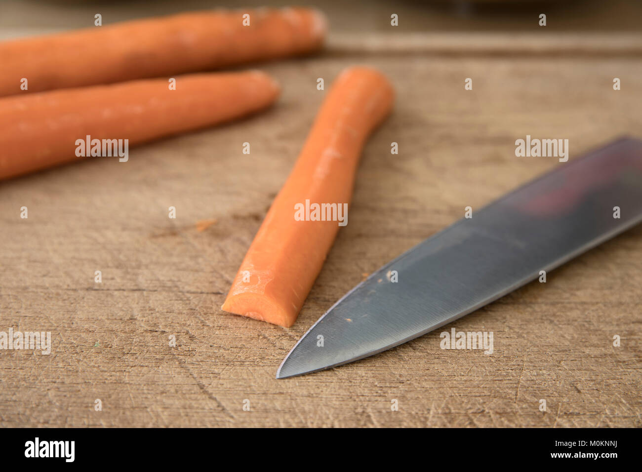 Messer Fähigkeiten Schneiden eine Karotte: Karotte und Kochmesser auf Schneidebrett. Stockfoto