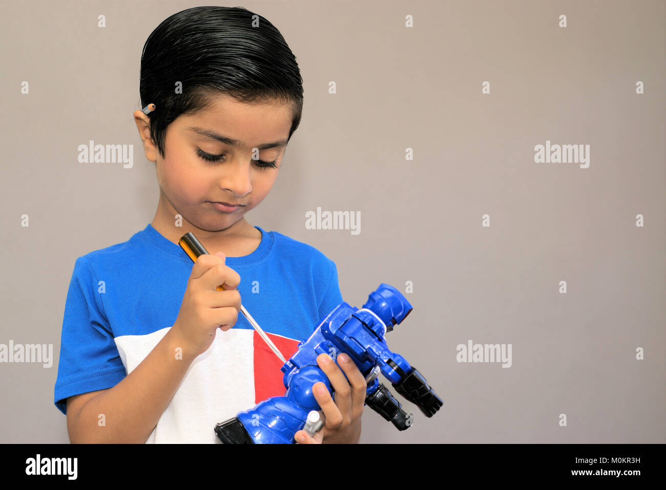 Kid Dinge zur Festsetzung. Kind mit einem Schraubendreher Spielzeug zu beheben. Konzept der geschäftigen Kid. Kind hat Bleistift hinter dem Ohr. Stockfoto