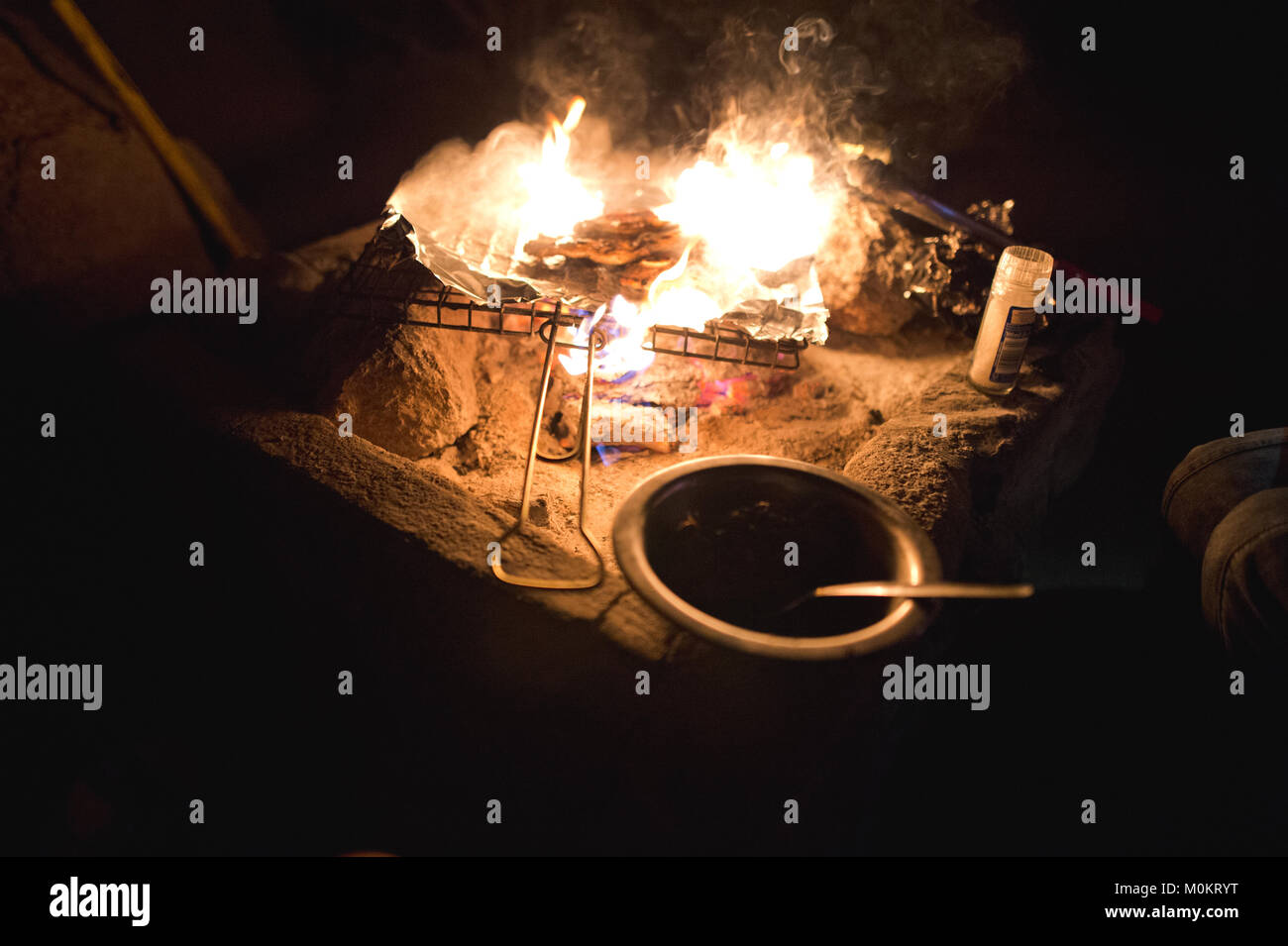 Ein braai Grill sitzt oben auf dem Lagerfeuer mit Flammen rund um das Essen. Stockfoto