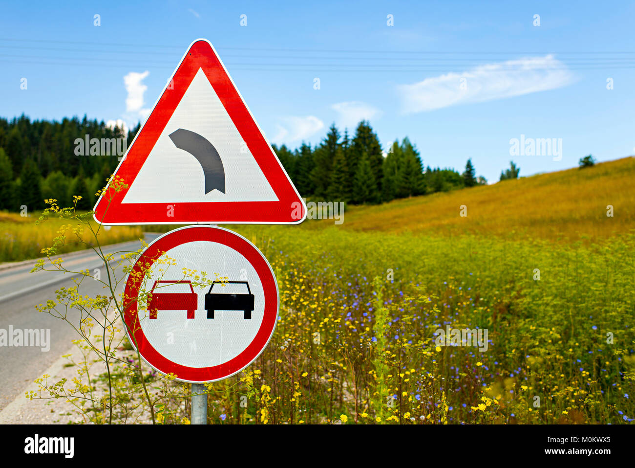 Verkehrszeichen auf einer Landstraße durch einen Berg Wiese Stockfoto