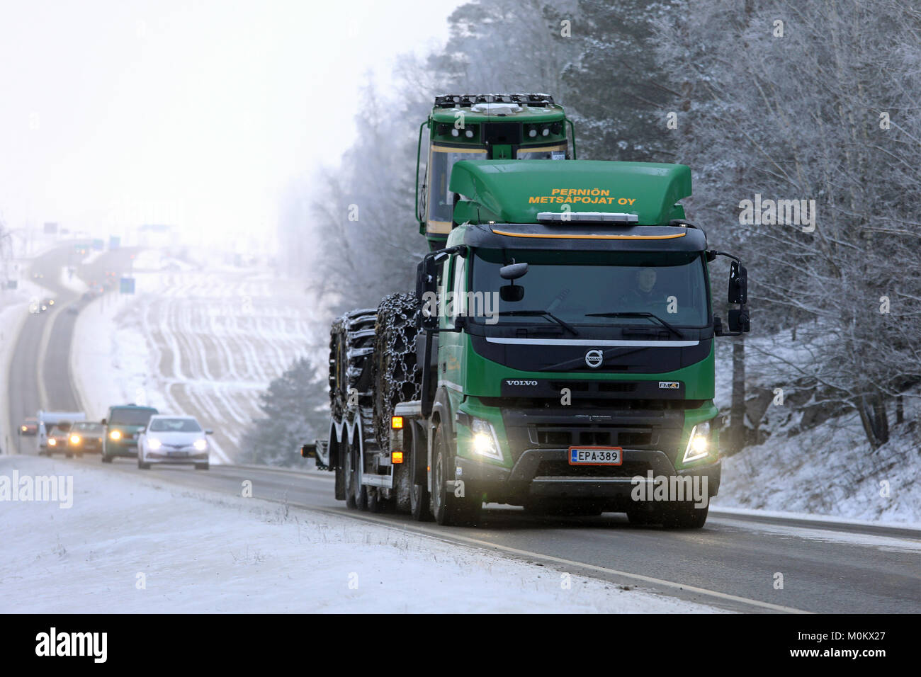 SALO, FINNLAND - Januar 20, 2018: Grün Volvo FMX Lkw hols John Deere Forstmaschinen auf Anhänger entlang der Landstraße im Winter Nebel. Stockfoto
