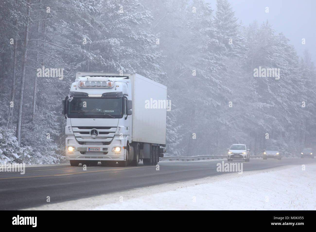 SALO, FINNLAND - Januar 20, 2018: Weiße Mercedes-Benz Actros Sattelschlepper transportiert Güter entlang nebliger Landstraße mit Autos im Winter. Stockfoto