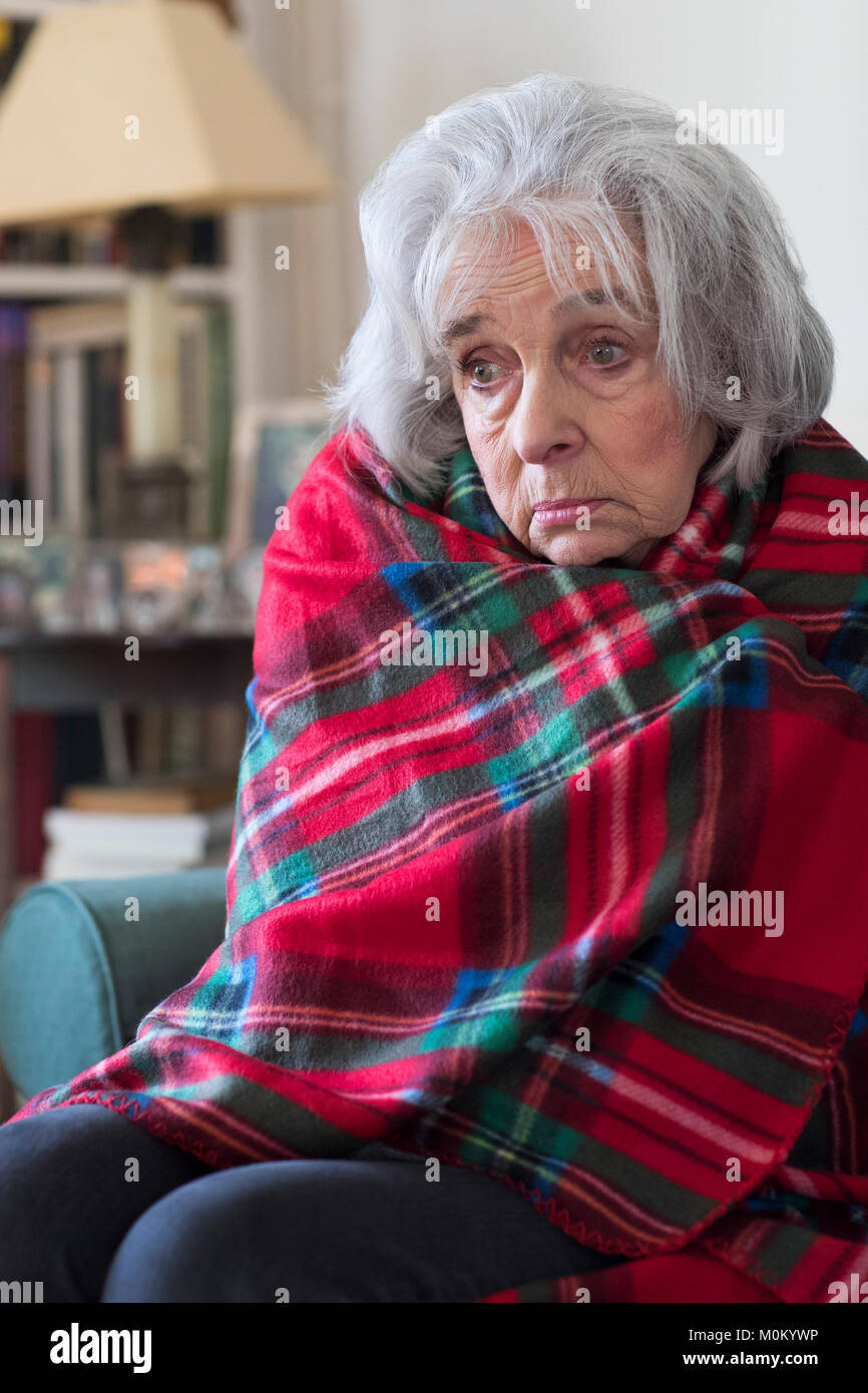 Ältere Frau, aufgewickelt in der Decke nicht Leisten Heizkosten Stockfoto