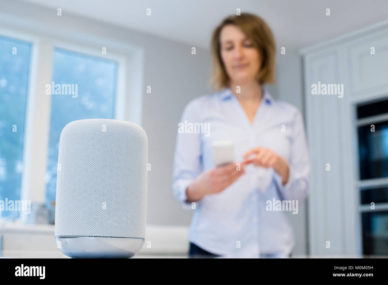 Frau Streaming Musik drahtlos vom Mobiltelefon zum Lautsprecher Stockfoto