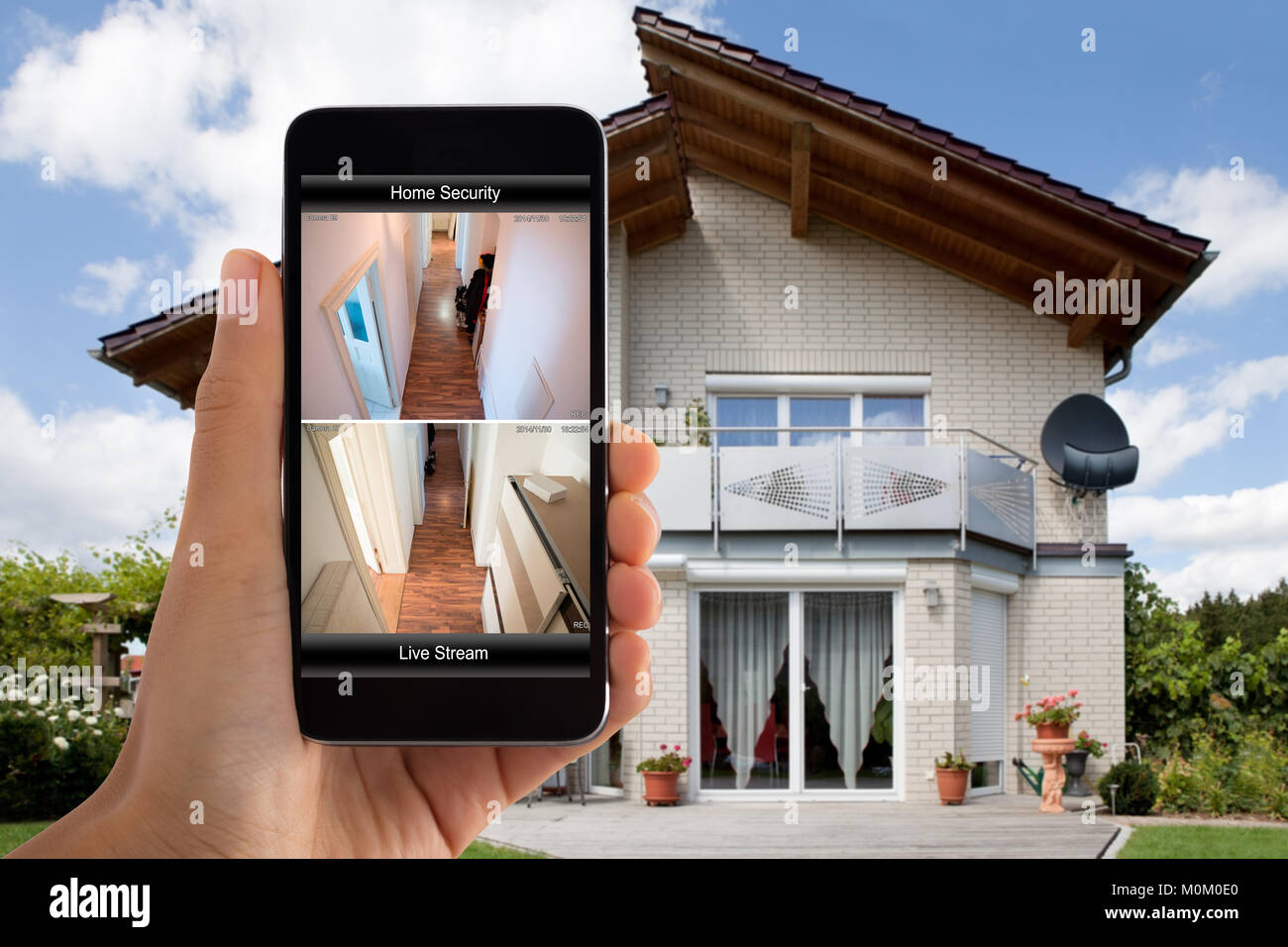 Nahaufnahme der Person Hand mit Home Security System auf Handy außerhalb des Hauses Stockfoto