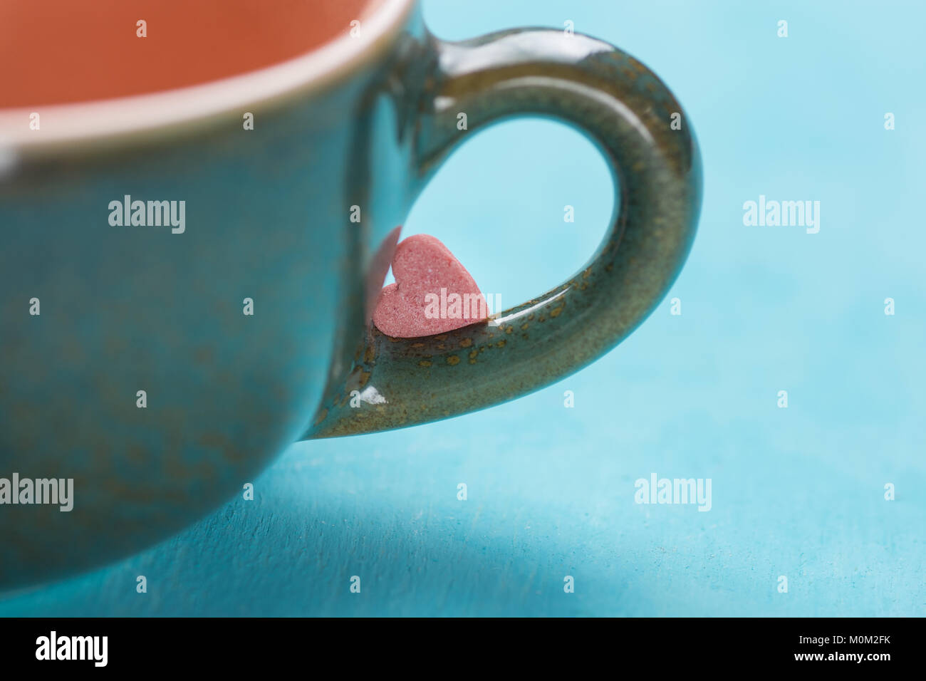 Kleine Rosa Rot Herzform Kandiszucker auf dem Griff von Kaffee Tasse Tee auf hellblauem Hintergrund. Valentinstag Muttertag Grußkarten Liebe Konzept. Stockfoto