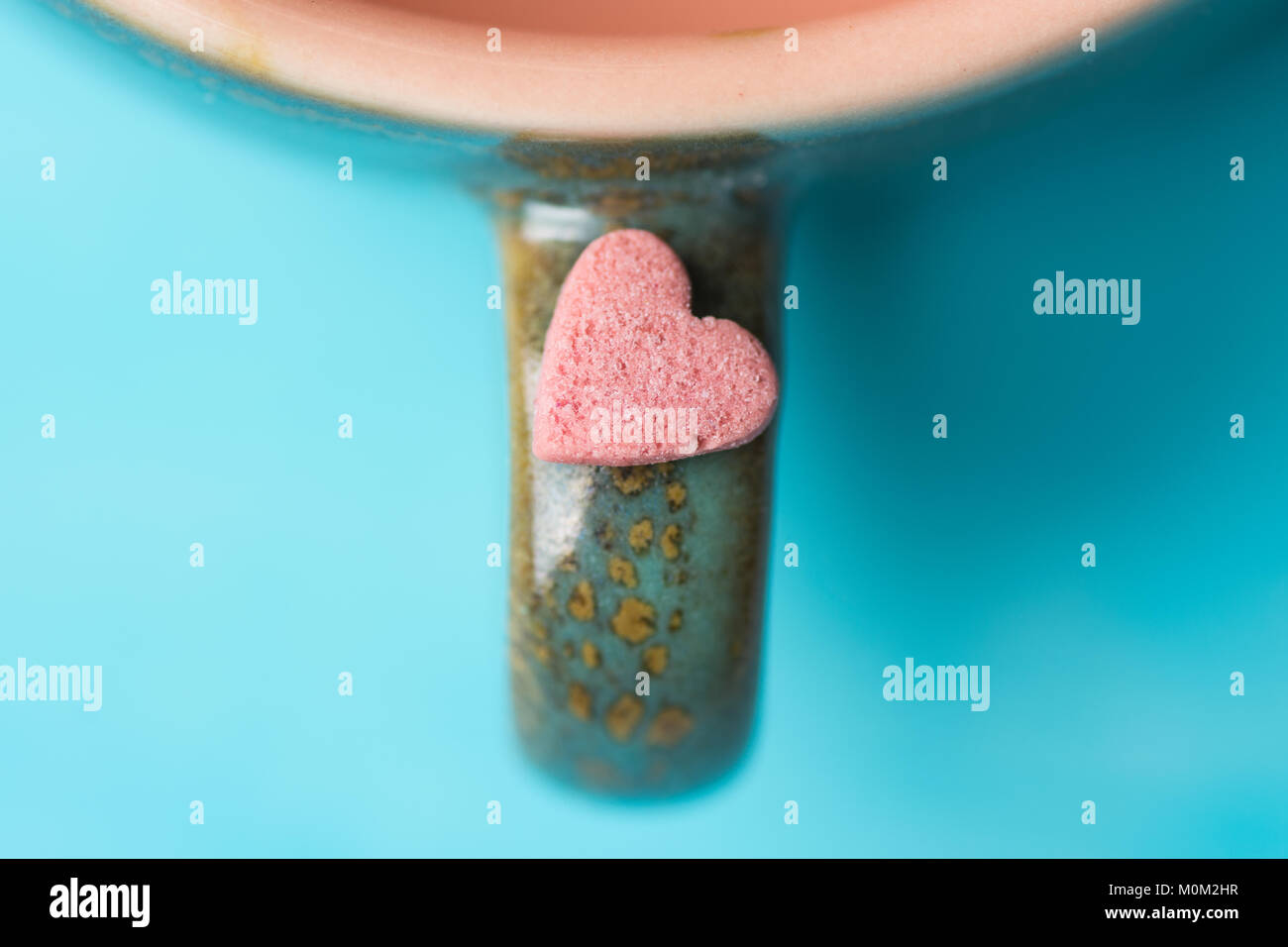 Kleine rosa Herzform Kandiszucker auf dem Griff von Kaffee Tasse Tee auf hellblauem Hintergrund. Valentinstag Muttertag Liebe Konzept. Grußkarte Post Stockfoto