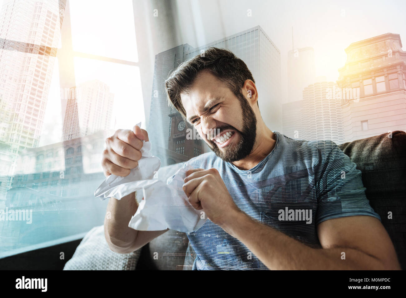 Crapping wütenden Mann sitzen und reißen Sie das Dokument. Stockfoto