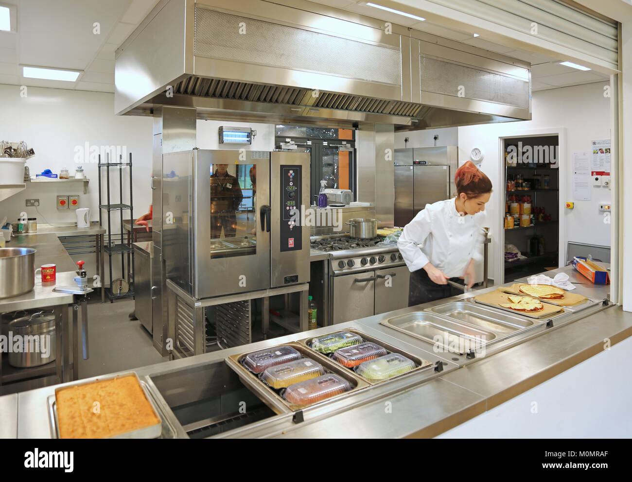 Ein catering Assistent bereitet die Schule Mittagessen in einer neuen Grundschule in London, UK. Stockfoto