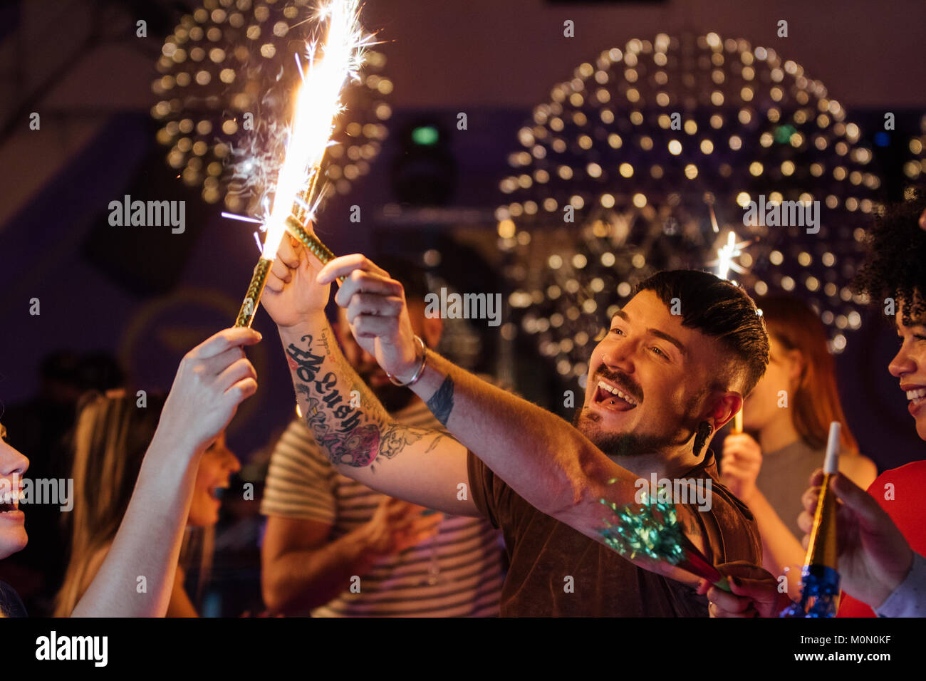 Freunde feiern gemeinsam in einem Nachtclub. Sie sind Beleuchtung innen Wunderkerzen beim Tanzen. Stockfoto