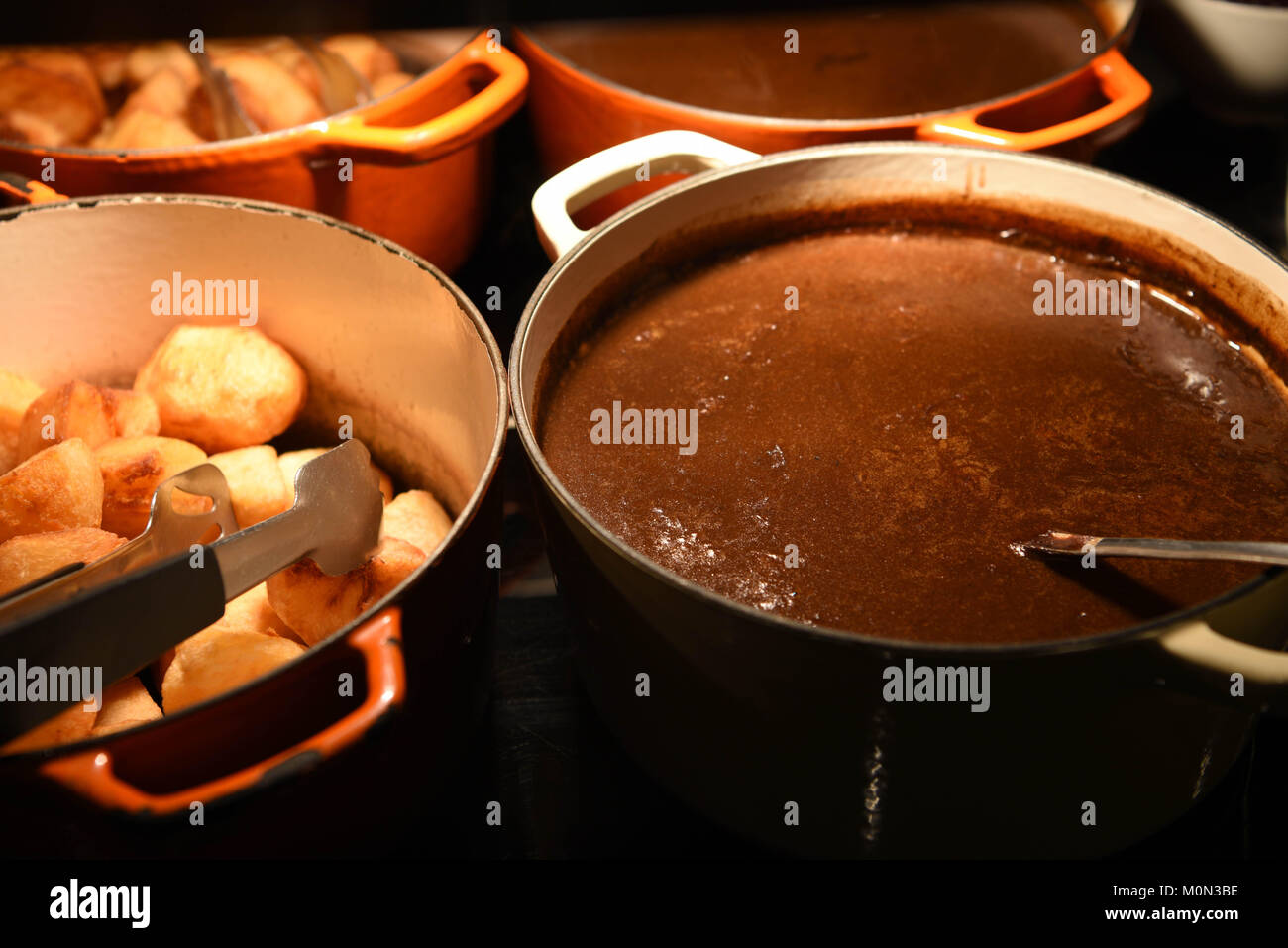 Essen Fotografie Bild des traditionellen Englischen golden knusprige Bratkartoffeln und erfahrene heiße Soße in Töpfe oder Pfannen bereit zu essen Stockfoto