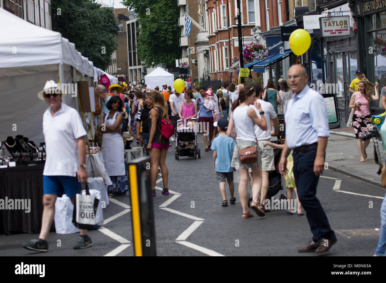 Menge Szene am Marlyebone Sommer Fayre Marlyebone Food Festival in London an einem sonnigen Tag mit gelben Luftballons und verpackt Marktstände Stockfoto