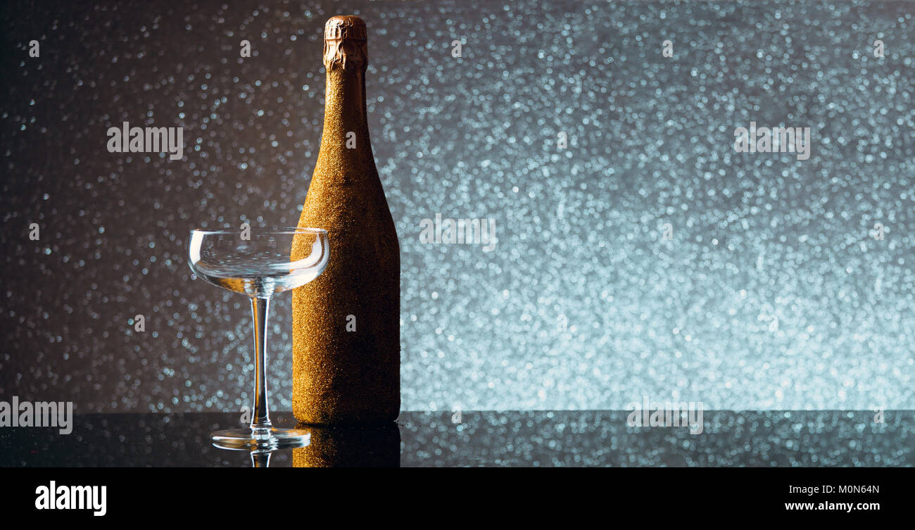 Bild der Flasche Champagner in Gold wrapper mit leeren Glas Wein auf grauem Hintergrund. Stockfoto