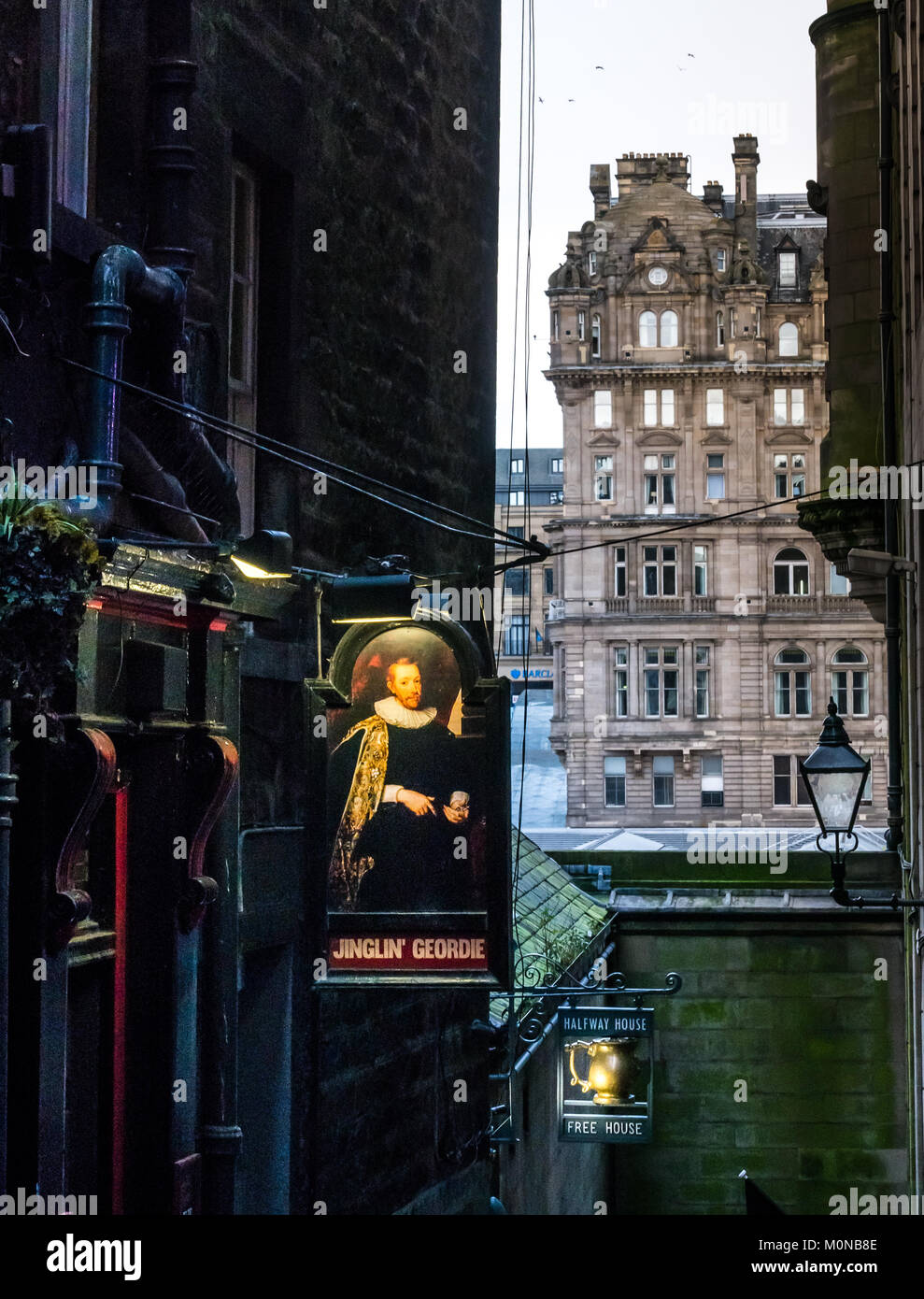 Pub Anzeichen für jinglin Geordie und Halfway House Pubs in dunklen Gasse, John Knox, Edinburgh, Schottland, Großbritannien, mit Balmoral Hotel im Hintergrund Stockfoto