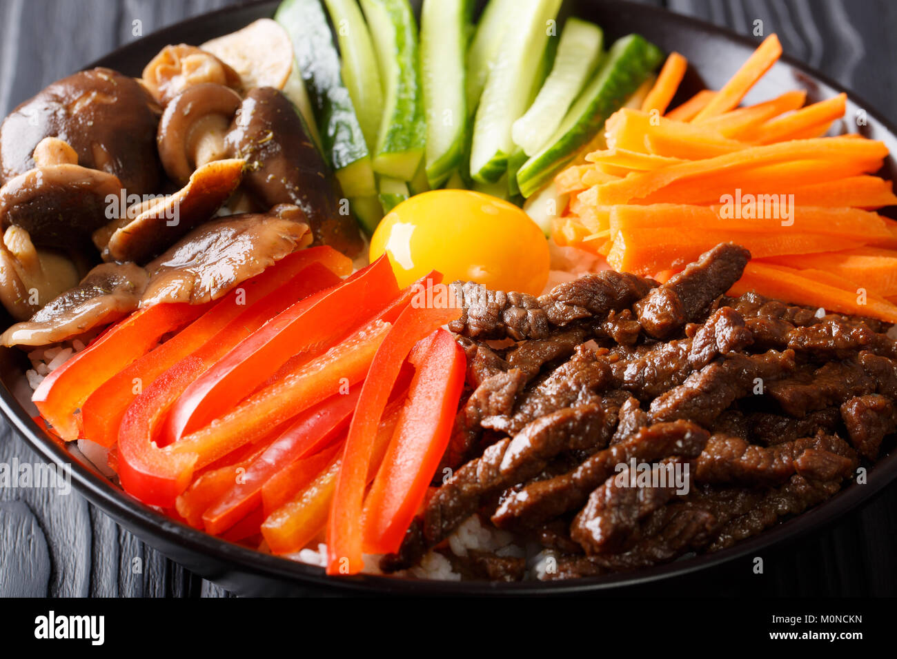 Köstlichen Bibimbap mit Rindfleisch, Eier, Gemüse, Shiitake und Reis close-up in einer Schüssel auf dem Tisch. Horizontale Stockfoto Köstlichen Bibimbap mit Rindfleisch, Eier, Gemüse, Shiitake und Reis close-up in einer Schüssel auf dem Tisch. Horizontale Stockfoto