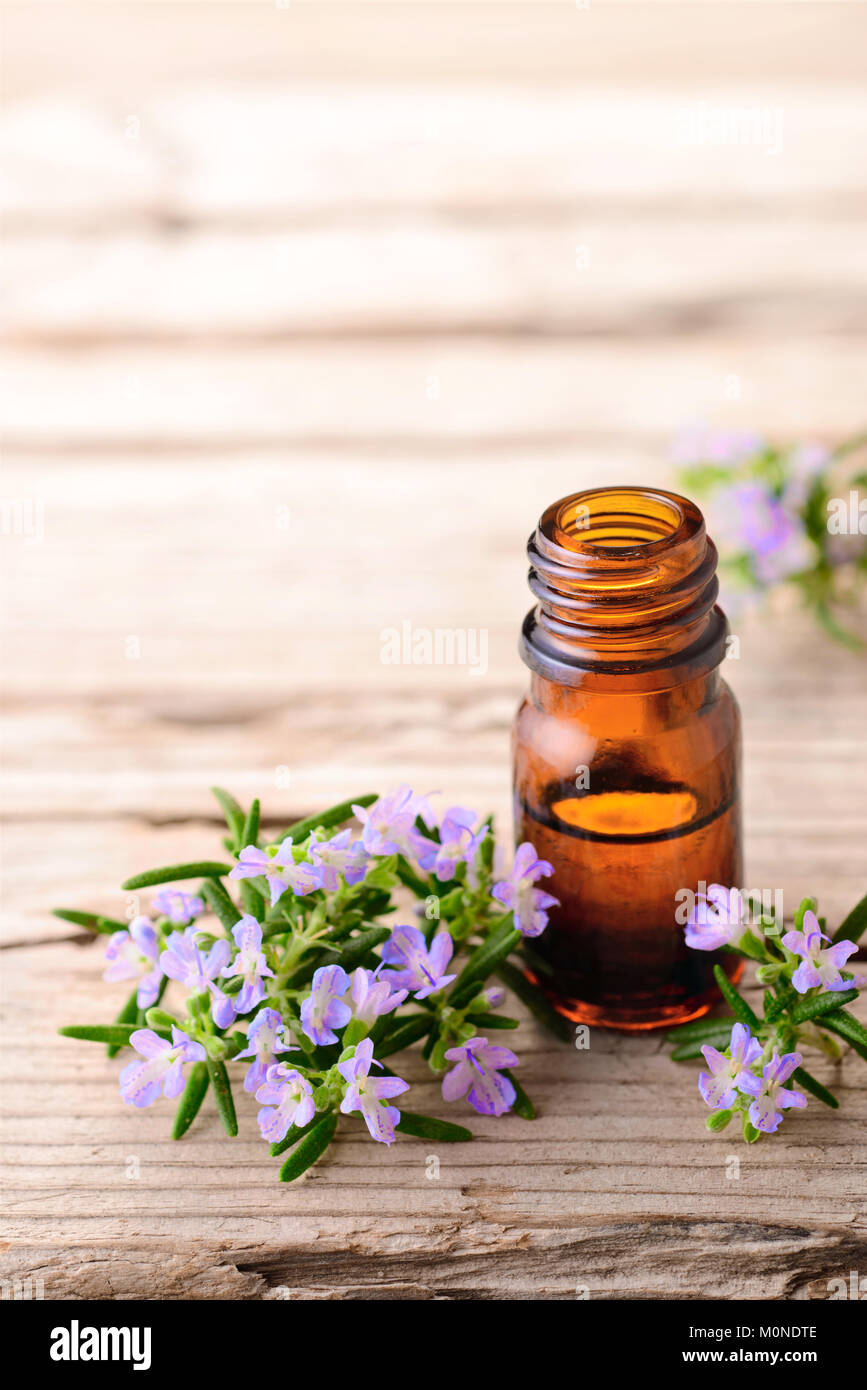 Rosmarin Massageöl und Blumen auf der Holzplatte Stockfoto