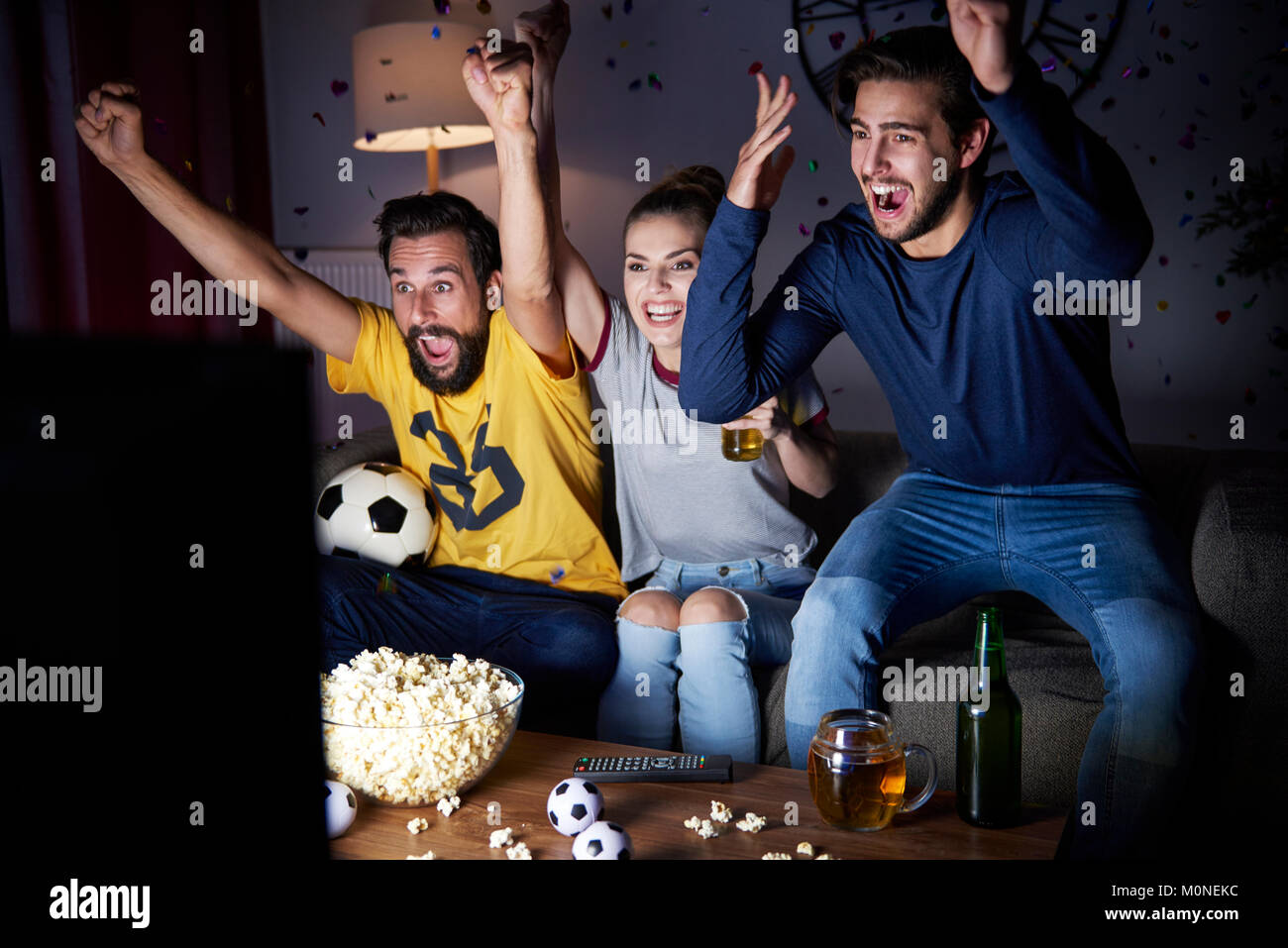 Aufgeregt Freunde sitzen auf dem Sofa Fernsehen Stockfoto