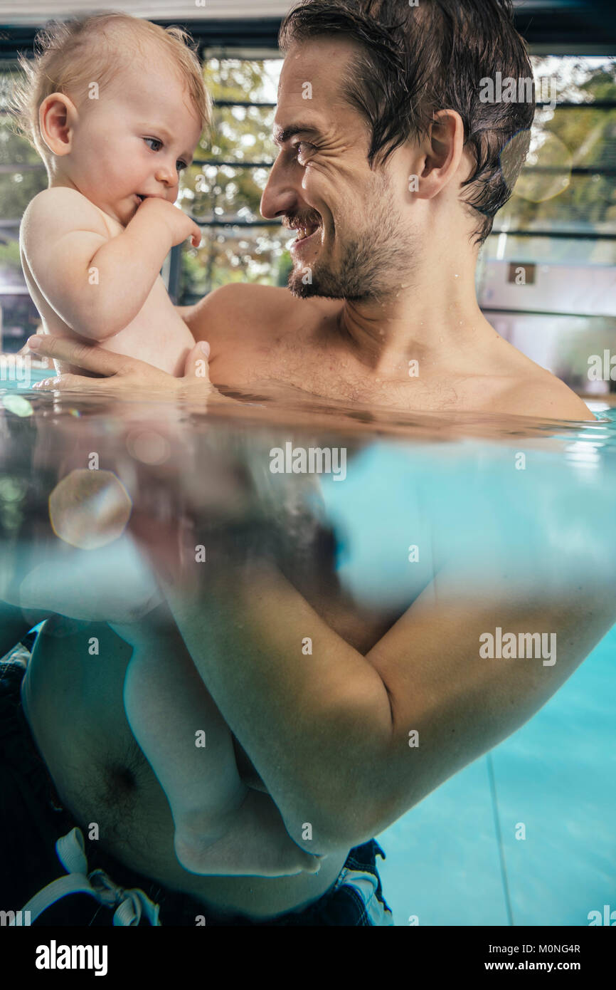 Vater Holding Baby im Hallenbad Stockfoto