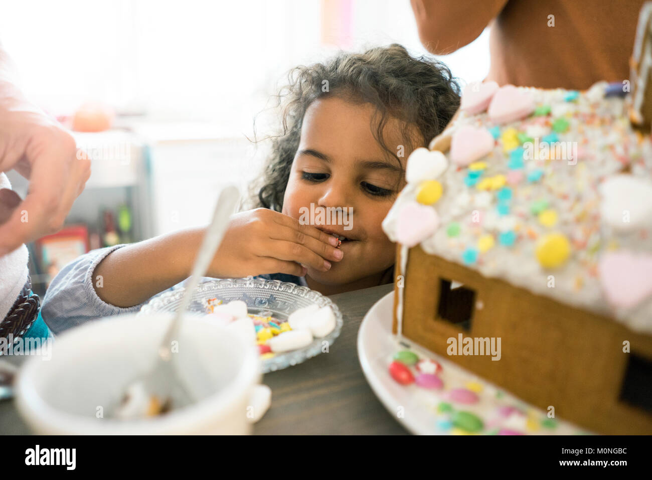 Wenig nibbeln Mädchen Süßigkeiten für Weihnachten Lebkuchenhaus Stockfoto