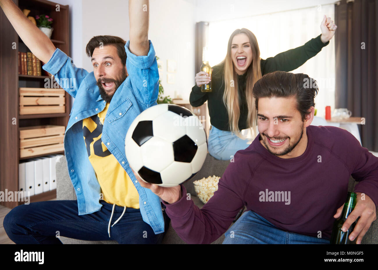 Aufgeregt Fußballfans vor dem Fernseher und jubeln Stockfoto
