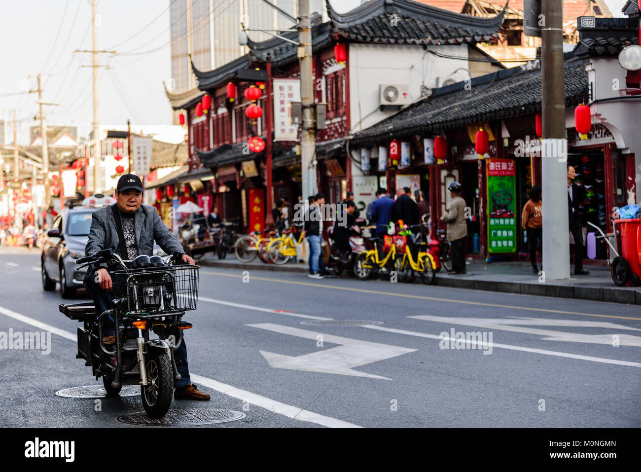 Shanghai, China. Ein Mann auf einem Moped wartet an einem roten Licht auf eine typische Straße in Shanghai, China. Credit: Benjamin Ginsberg Stockfoto