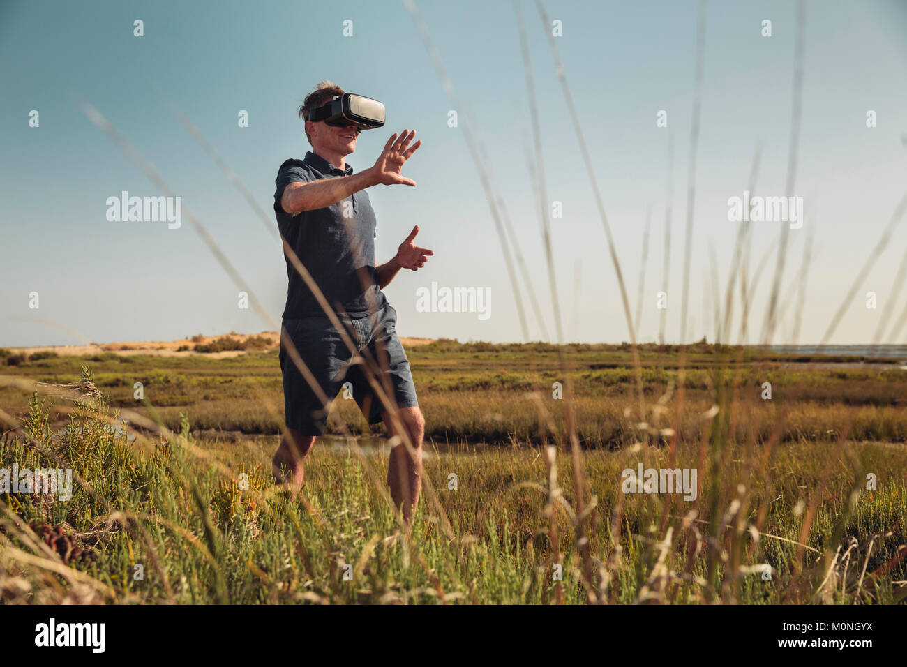 Reifen Mann mit VR-Brille zu Fuß durch Gras Stockfoto