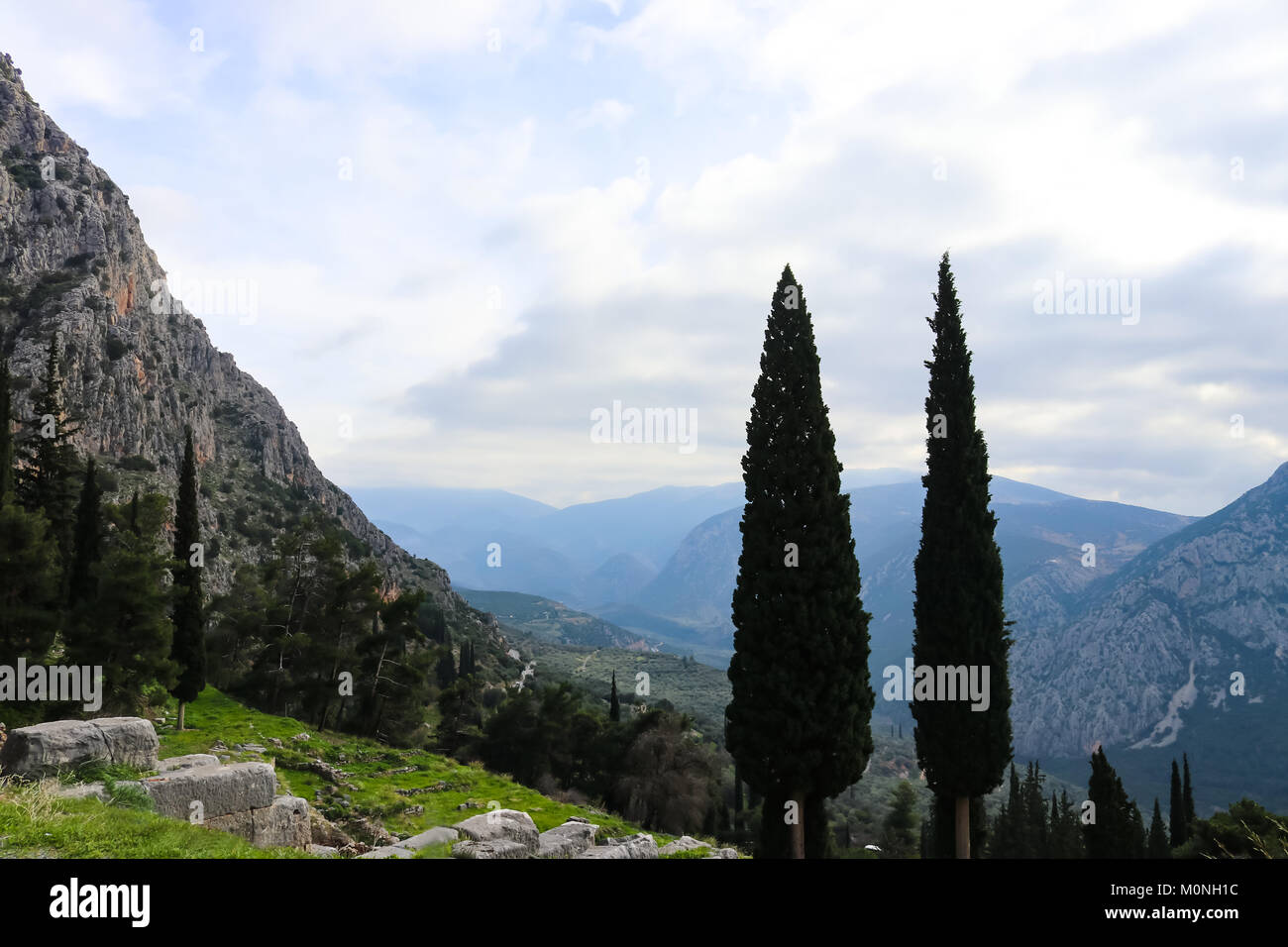 Bergige Landschaft in Griechenland mit Zypern Bäumen im Vordergrund von Delphi Ruinen hoch in Berge gesehen Stockfoto