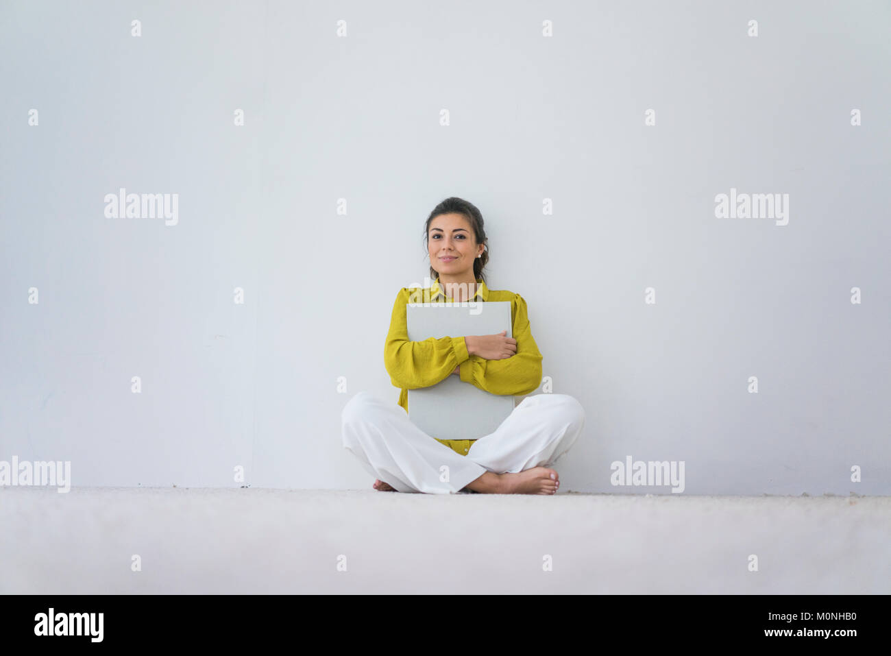 Porträt der lächelnde Frau mit einem übergroßen Buch sitzen auf dem Boden Stockfoto
