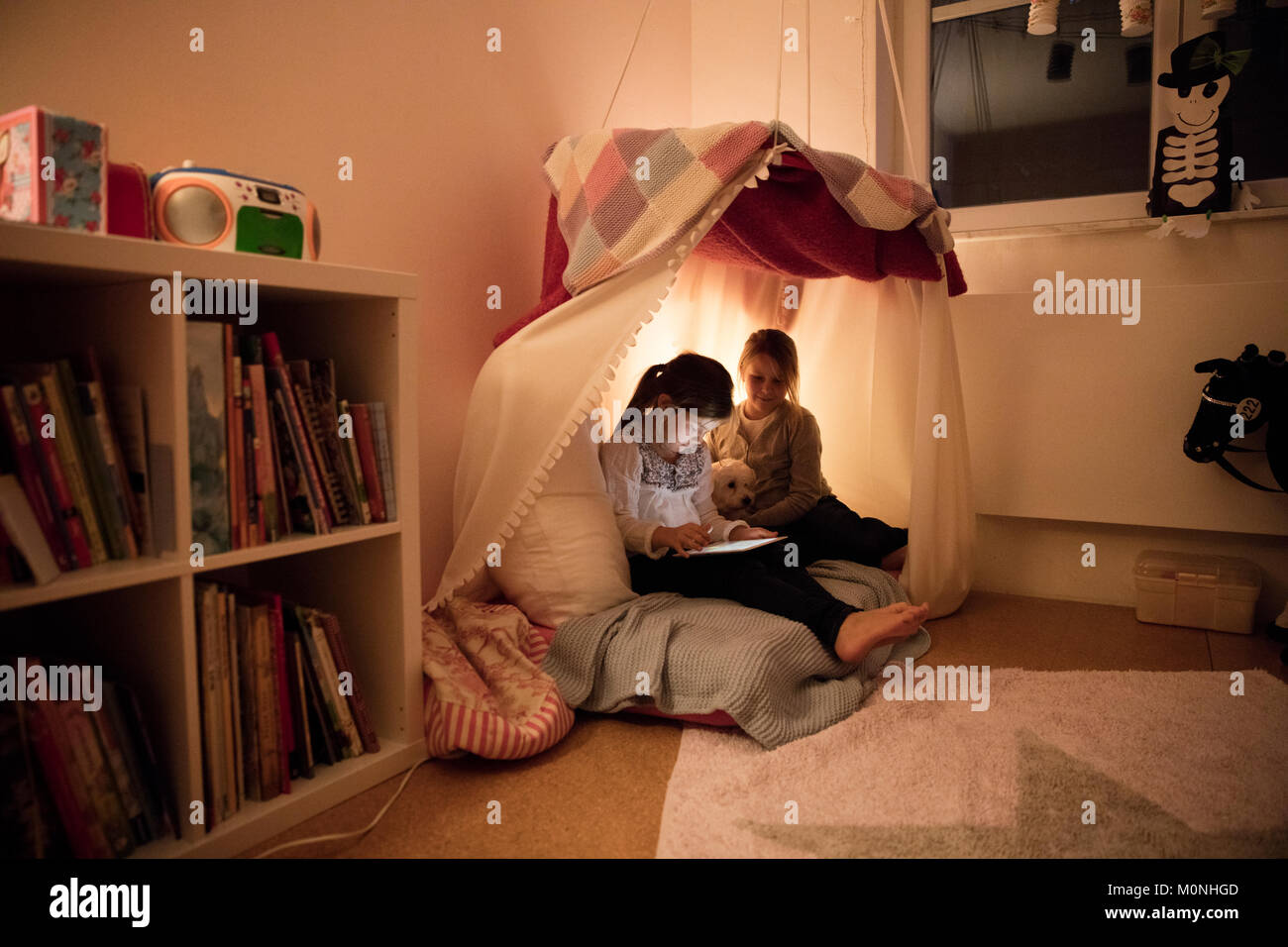 Zwei Mädchen mit Hund und Tablette im Kinderzimmer Stockfoto