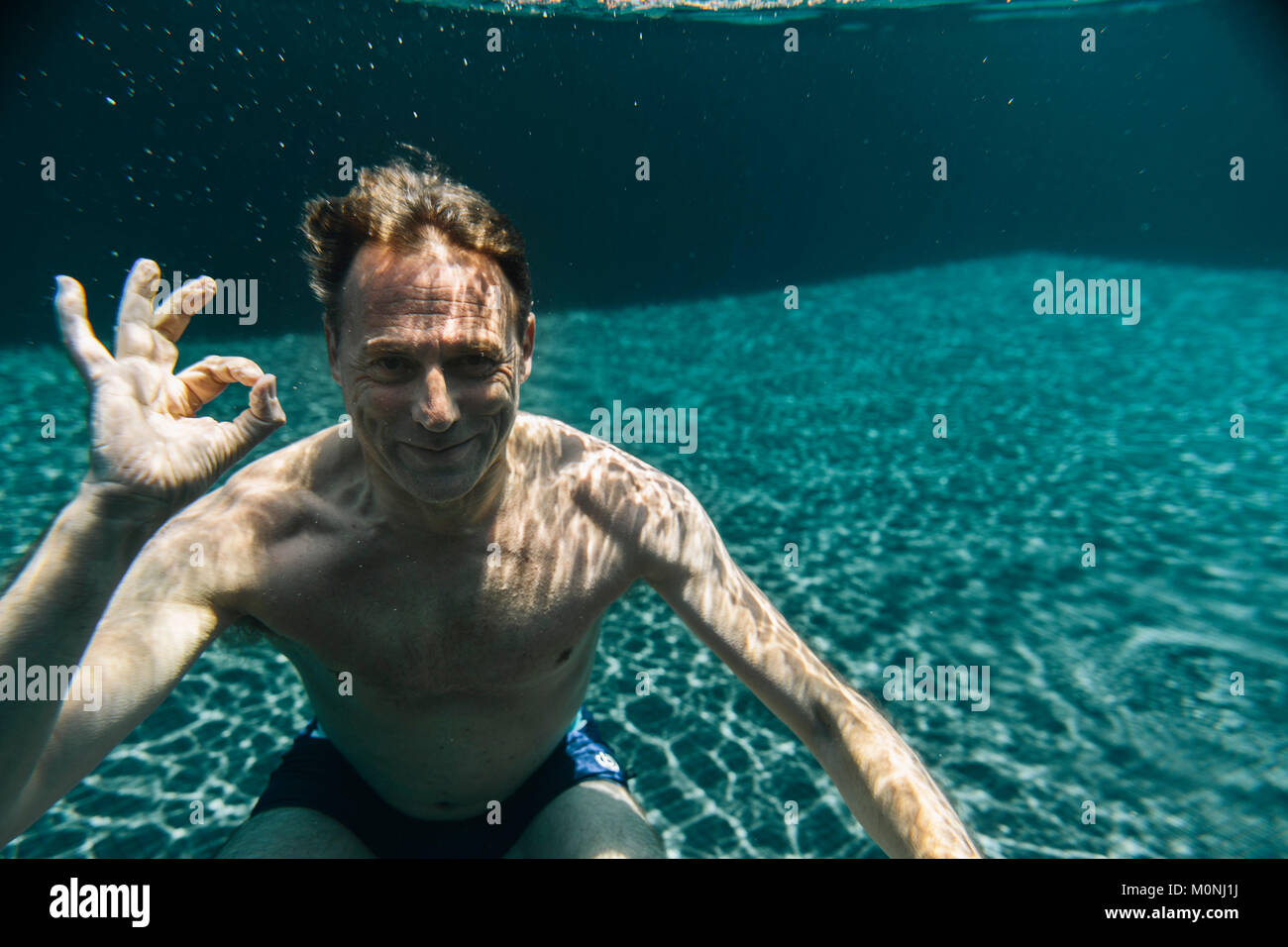 Portrait von lächelnden Mann Unterwasser in einem Schwimmbad machen ok Zeichen Stockfoto