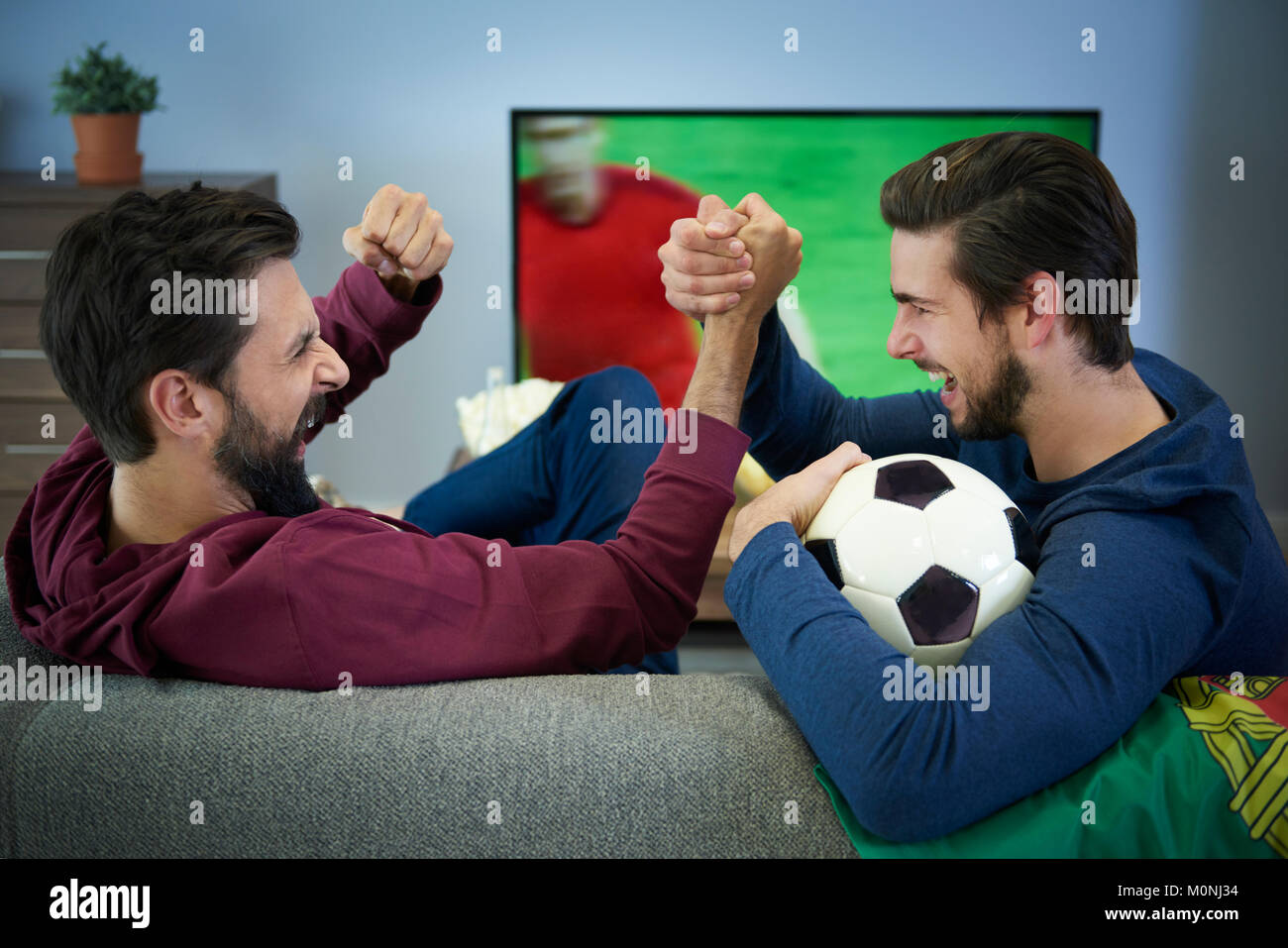 Zwei Fußballfans, Fernsehen und jubeln Stockfoto