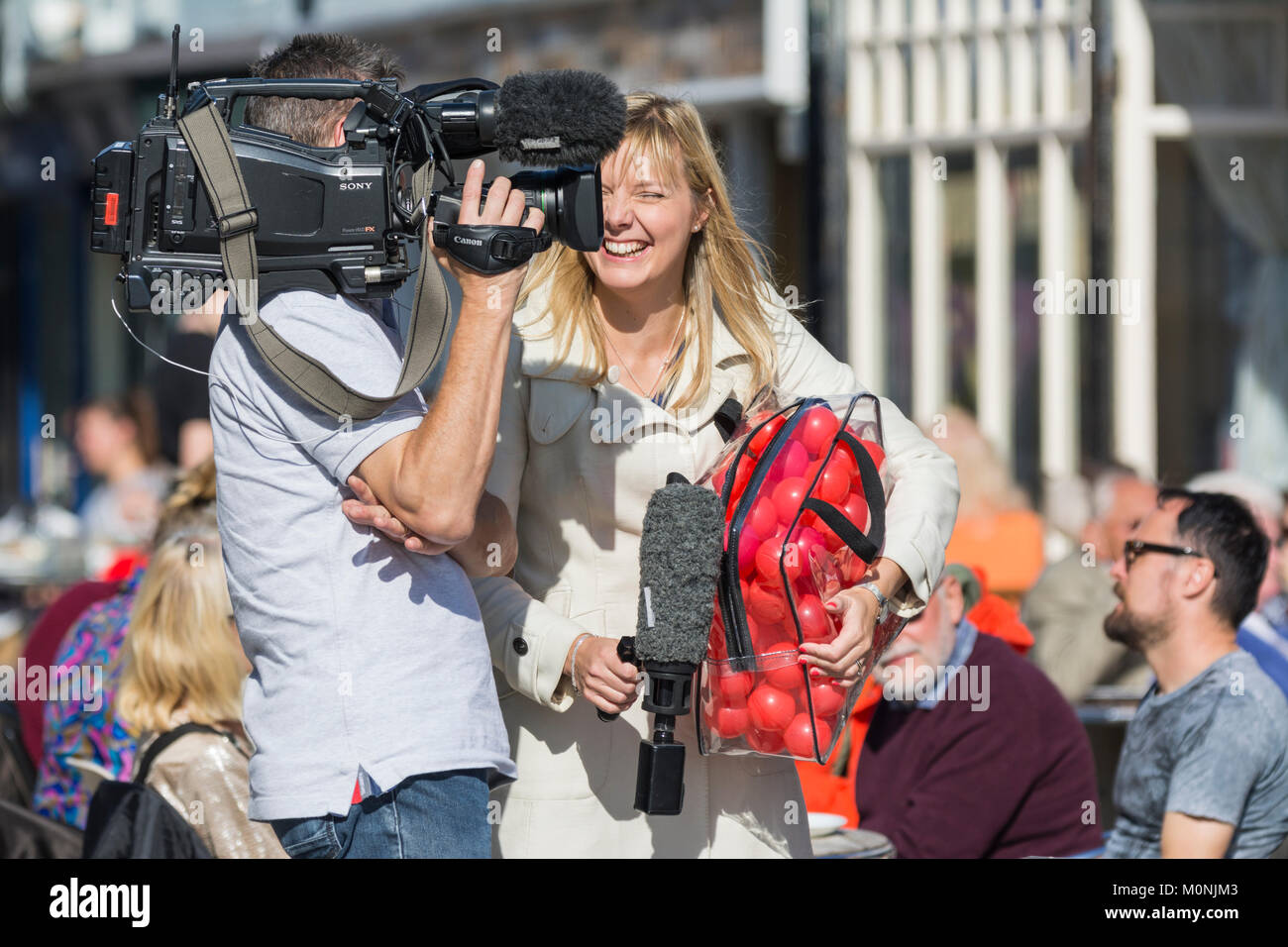 Weibliche TV-Moderator Lachen und Lächeln für den Job, auf einem Übertragungswagen in Großbritannien. Stockfoto
