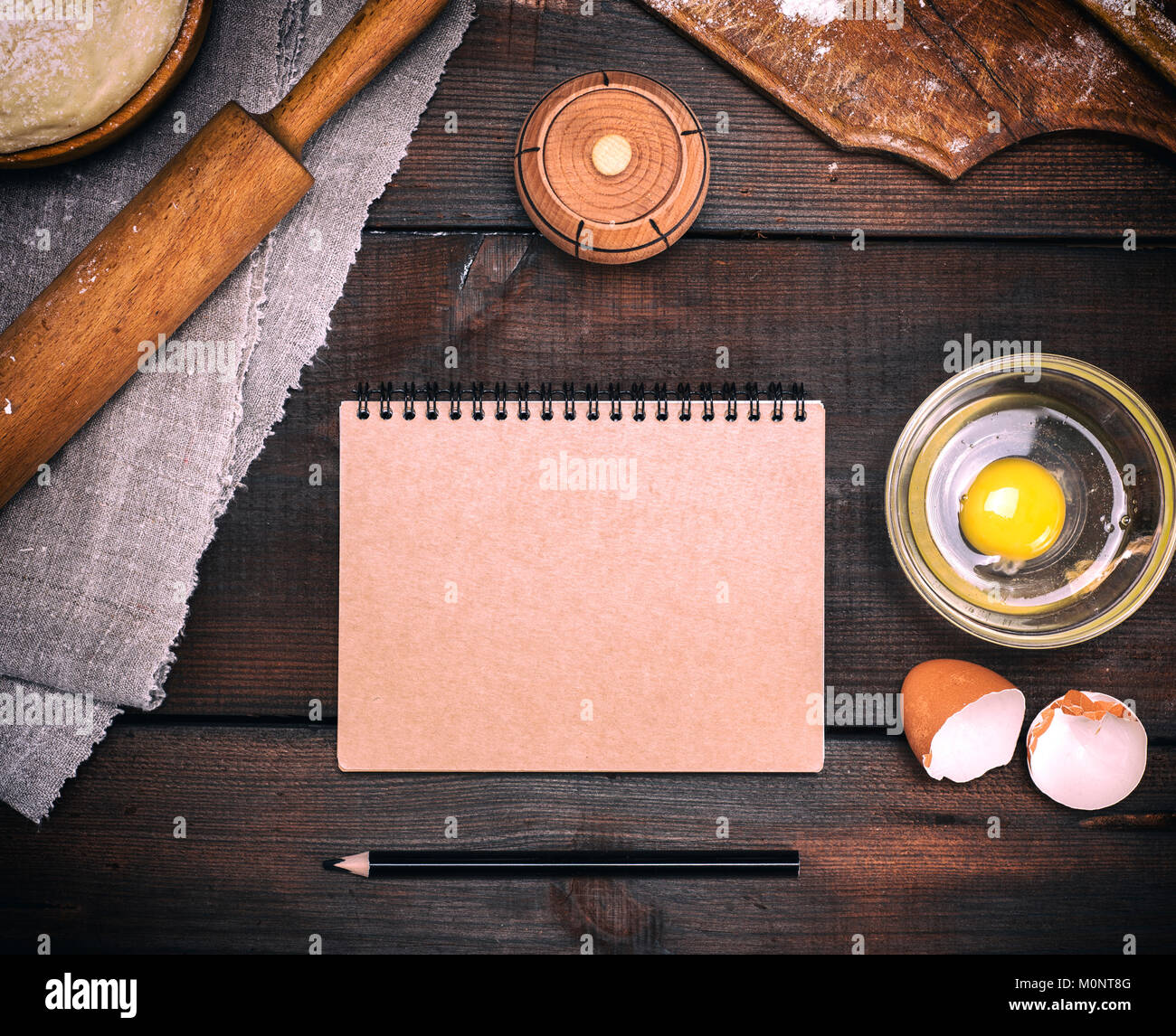 Leeren Notizbuch aus Papier mit braunen Seiten ein Rezept für Teig Gerichte aufzeichnen, neben einem Ei und eine Küchenrolle, Ansicht von oben Stockfoto