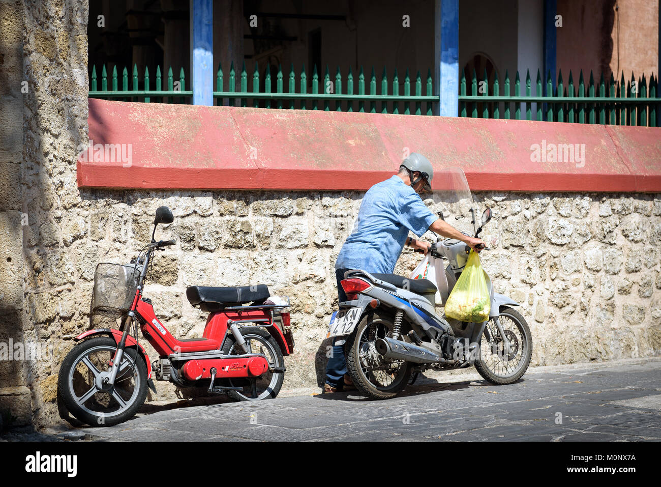 RHODES, Griechenland - AUGUST 2017: alte Mann ist der Motor von seinem Motorrad Stockfoto