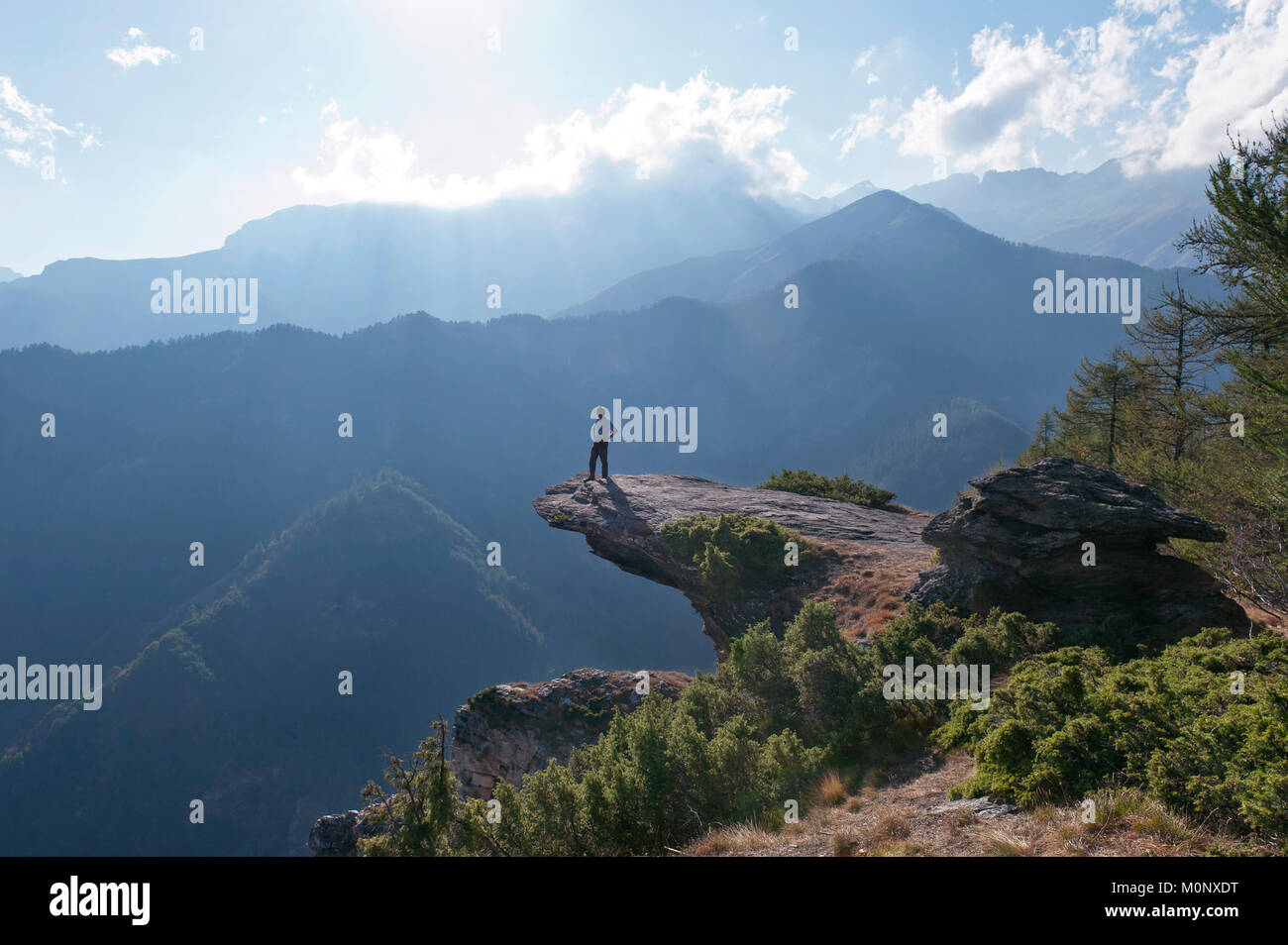 Mann stand auf Prominente hervorstehenden Felsen, Colle San Giovanni in der Nähe Elva, Valle Maira, Provinz Cuneo, Cottischen Alpen, Piemont Stockfoto