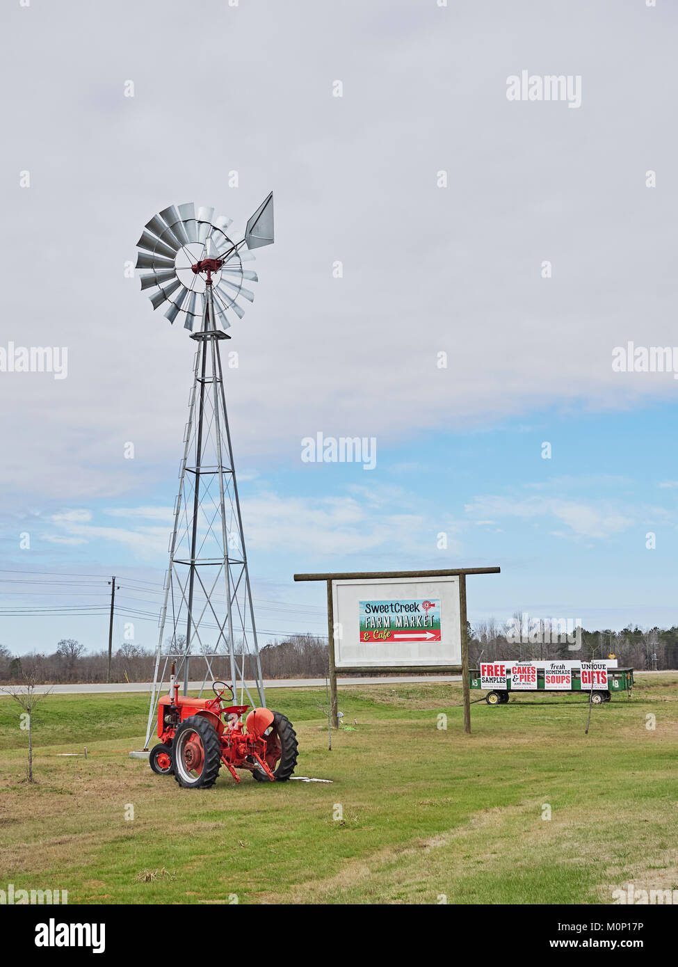 Schilder am Straßenrand, ein roter Traktor und ein Windrad Wasserpumpe. Der Bauernhof Markt in ländlichen Hecht Straße Alabama in den Usa werben. Stockfoto