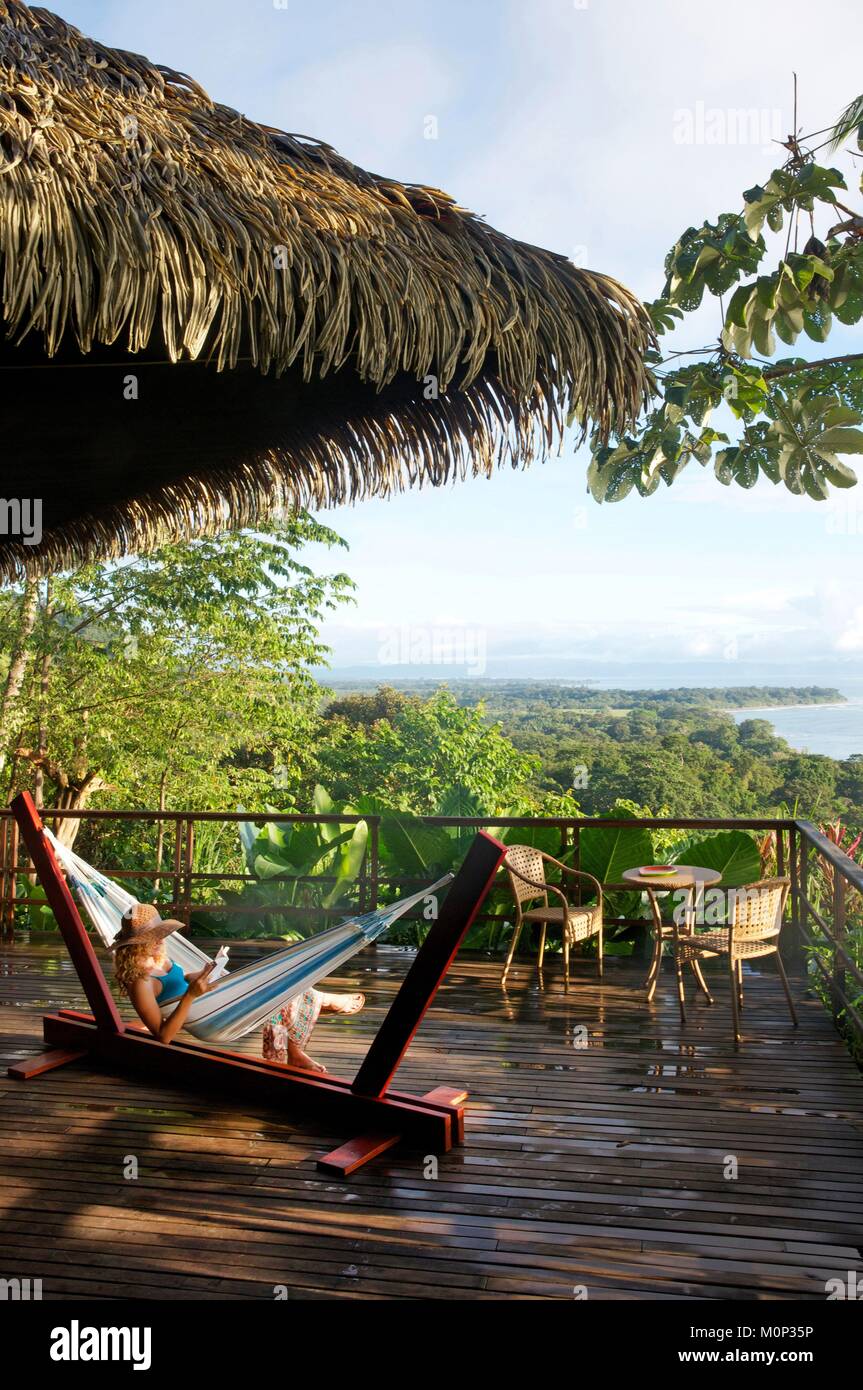 Costa Rica, Halbinsel Osa, junge Frau mit Strohhut in Ihrer Hängematte auf der Terrasse fo der Ecolodge Lapa Rios mit Blick auf den Wald und den Pazifischen Ozean Stockfoto Costa Rica, Halbinsel Osa, junge Frau mit Strohhut in Ihrer Hängematte auf der Terrasse fo der Ecolodge Lapa Rios mit Blick auf den Wald und den Pazifischen Ozean Stockfoto