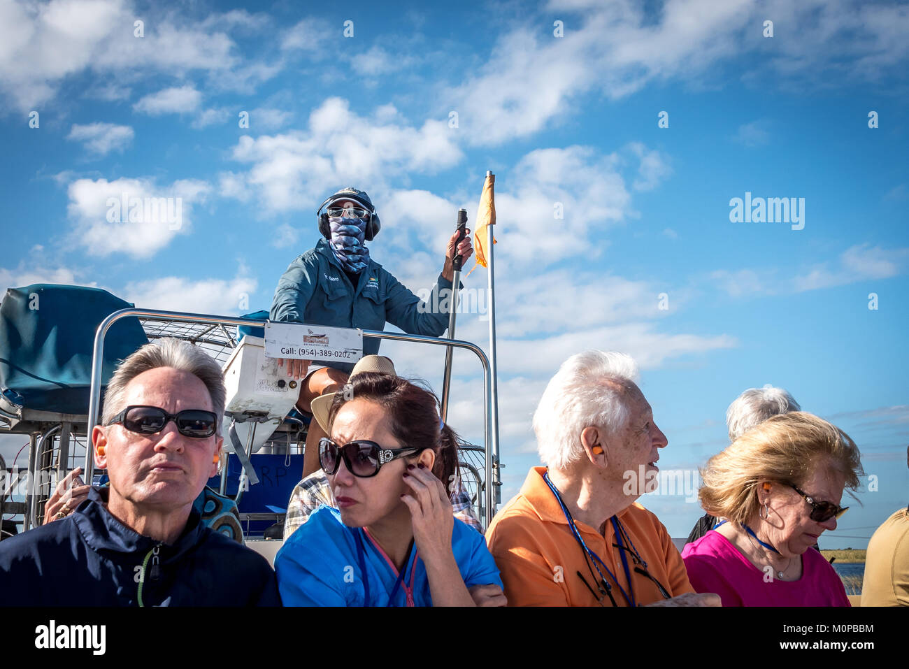Touristen und Kapitän auf einem Luftboot in Florida Everglades bei Sawgrass Recreation Park (auch Air Boot), Suchen der Kapitän in Bandana und Sound supressors Stockfoto