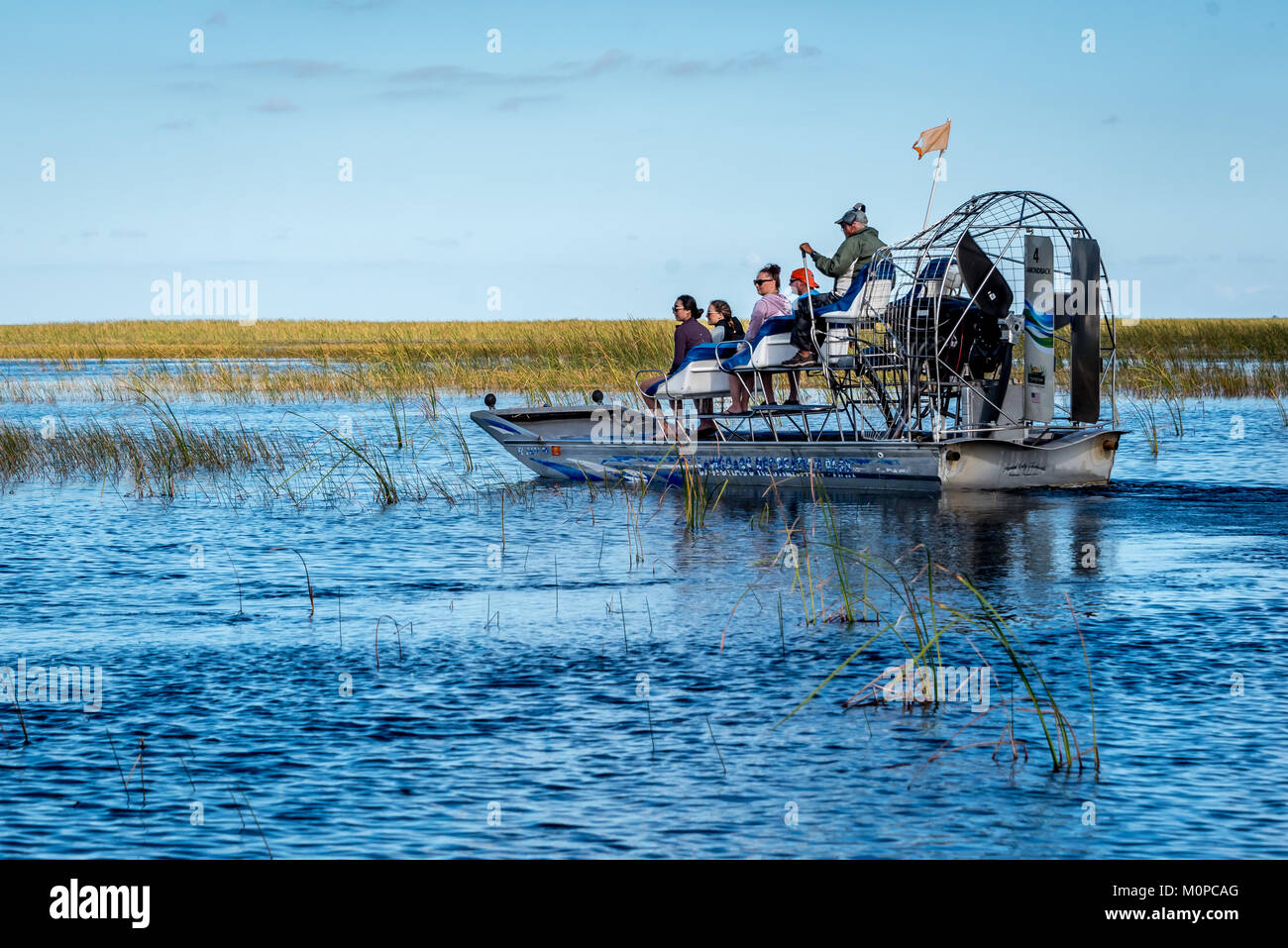 Touristen auf der Yacht in den Florida Everglades bei Sawgrass Recreation Park, airboat Kapitän fahren kleine Gruppe durch Fluss aus Gras (auch Air Boot) Stockfoto