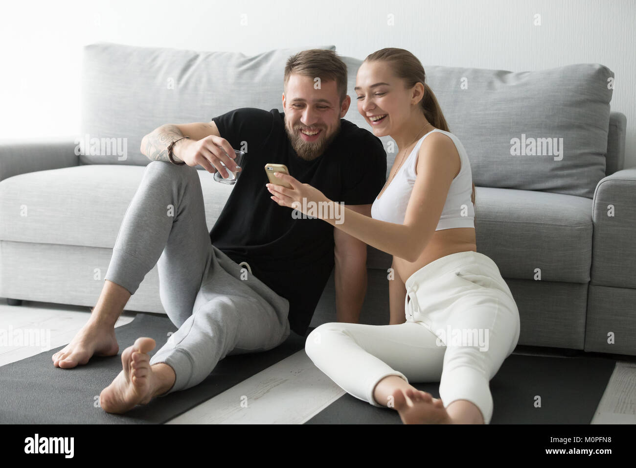 Passen glückliches Paar mit Smartphone App für Training zu Hause Stockfoto