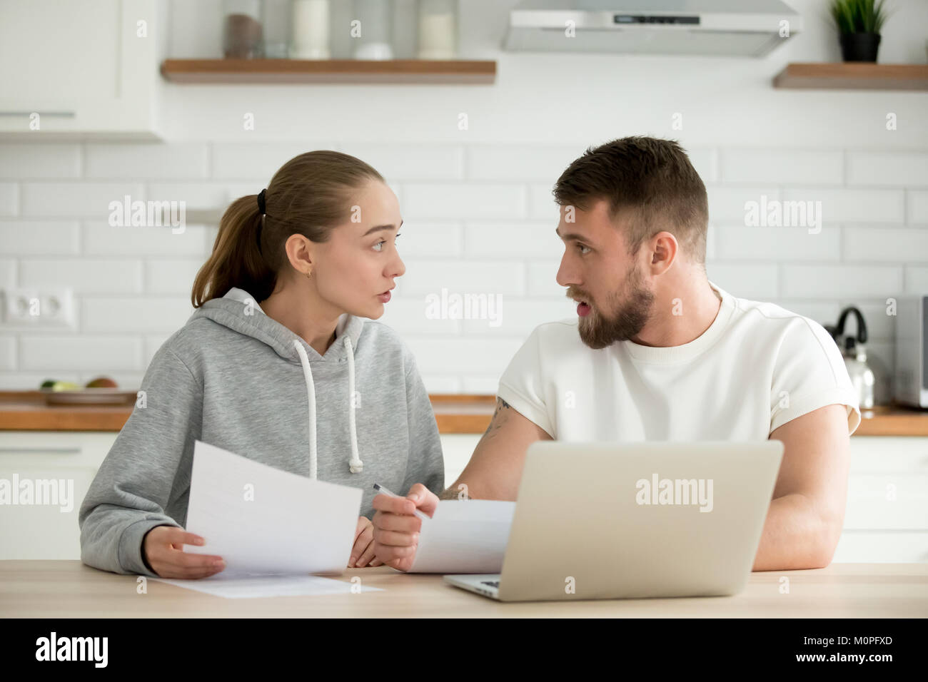 Junges Paar über Rechnungen oder Dokument zu Hause Küche streiten Stockfoto