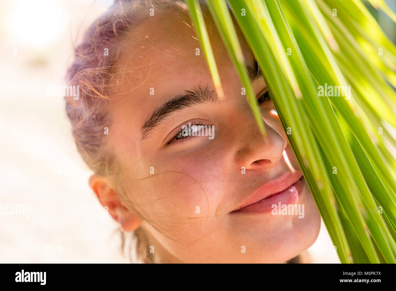 Porträt eines lächelnden jungen Frau mit Palmenblättern Stockfoto