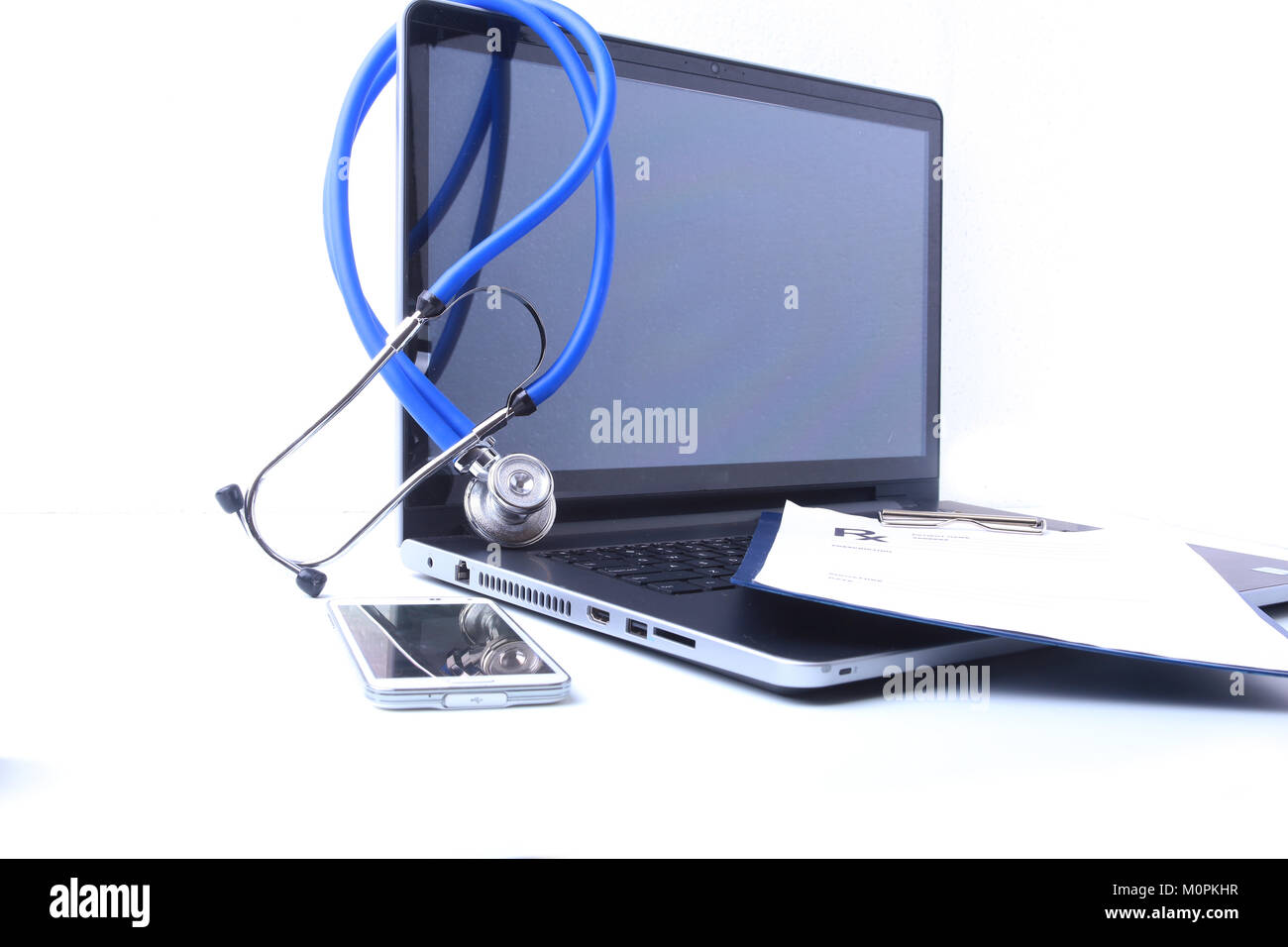 Eine medizinische Stethoskop in der Nähe von einem Laptop auf einen hölzernen Tisch, weiß Stockfoto
