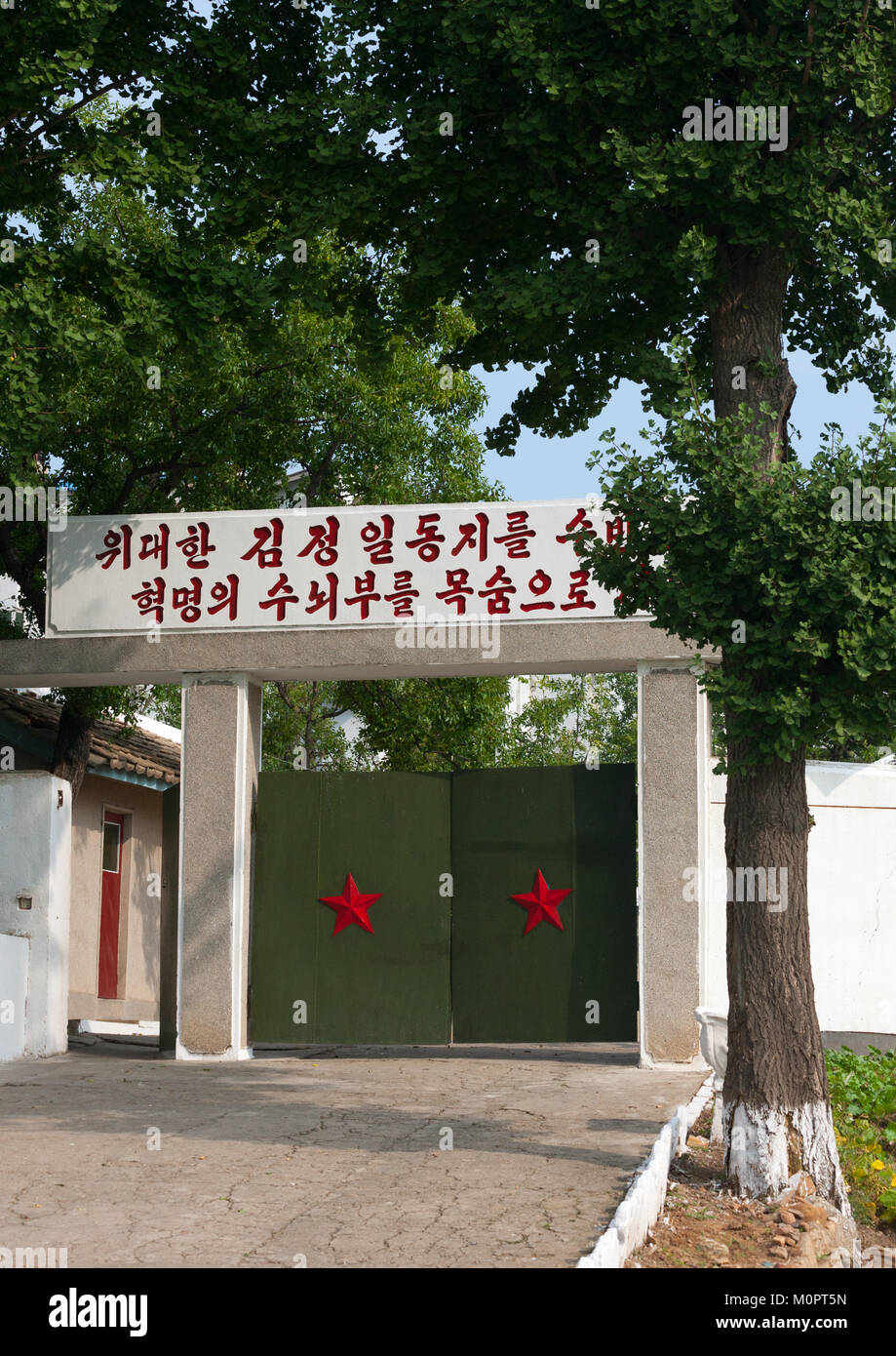 Eingangstor mit roten Sternen und eine propagandistische Parole oben, Kangwon Provinz, Chonsam kooperative Farm, Nordkorea Stockfoto