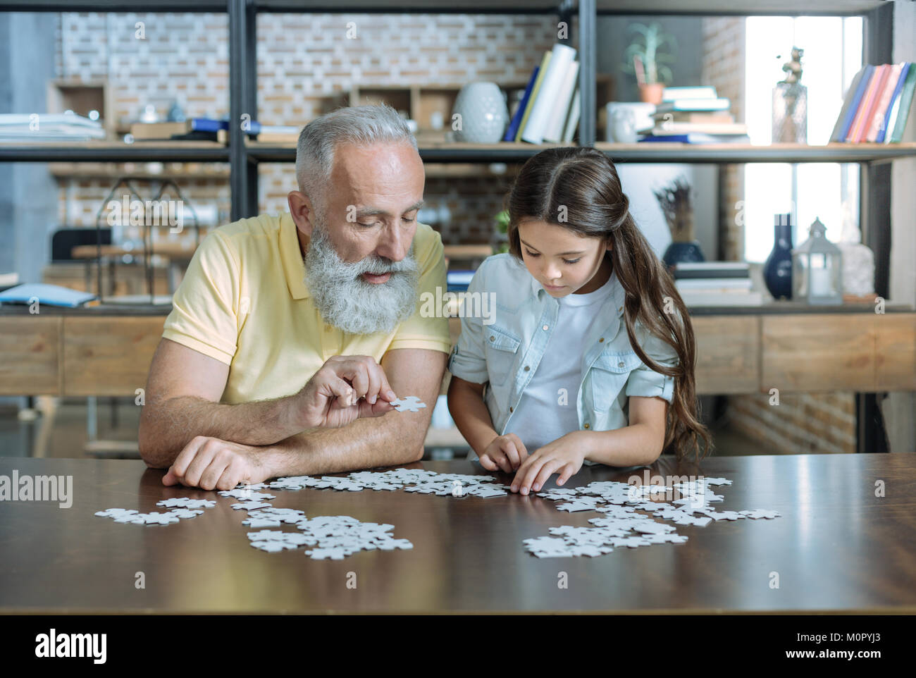 Konzentrierte sich zwei Generationen der Familie spielen puzzle Spiel zusammen Stockfoto